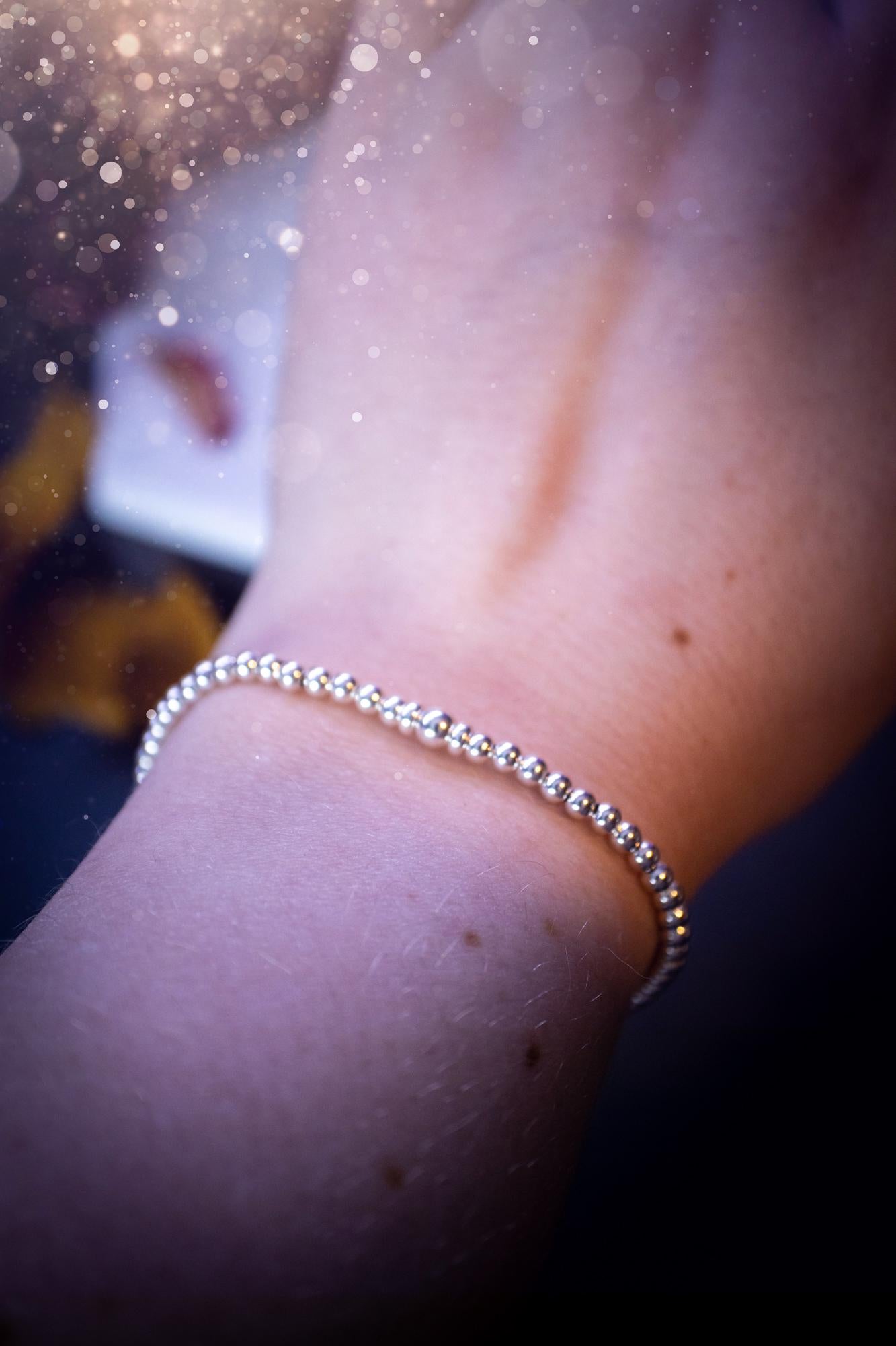 Beautiful and handmade, 3mm beaded, sterling silver stacking bracelet. This bracelet has been made using high quality sterling silver beads which have bee strung on strong 49 strand beading wire. This wire is very strong, but also gives a beautiful drape across the wrist. Featuring one larger silver spacer bead in the middle with rondelle beads either side to give some uniqueness. This bracelet is ideal for stacking with others, and makes a lovely gift for jewellery lovers.