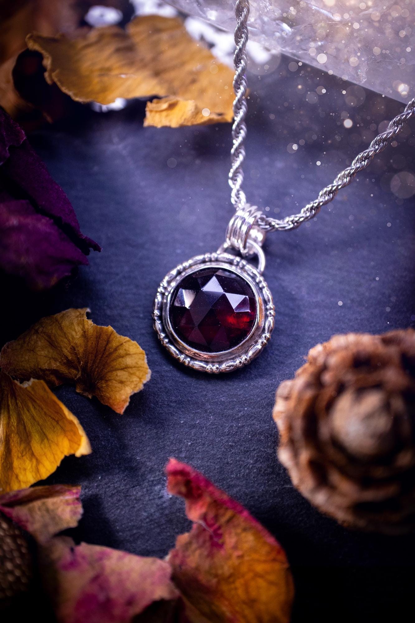 Handmade sterling silver pendant necklace featuring a circular design with a deep red garnet crystal centrepiece, showcasing a minimalist yet elegant artisan style. This piece has been created using recycled fine and sterling silver and features a gorgeous rose cut garnet that is full of sparkle. Suitable or special occasions such as birthdays, anniversaries, graduations and more. Garnet is the birthstone for January. Witchy and gothic handmade jewellery.