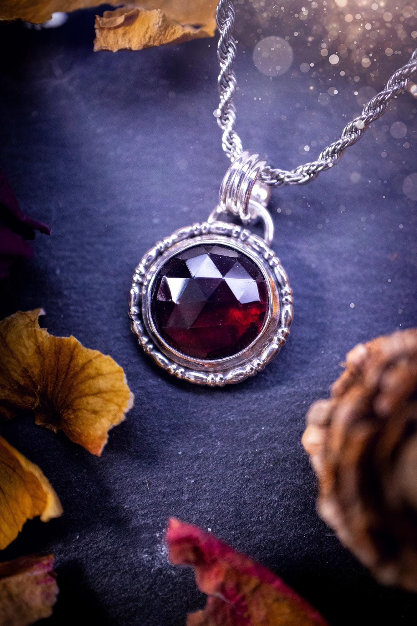 Handmade sterling silver pendant necklace featuring a circular design with a deep red garnet crystal centrepiece, showcasing a minimalist yet elegant artisan style. This piece has been created using recycled fine and sterling silver and features a gorgeous rose cut garnet that is full of sparkle. Suitable or special occasions such as birthdays, anniversaries, graduations and more. Garnet is the birthstone for January. Witchy and gothic handmade jewellery.