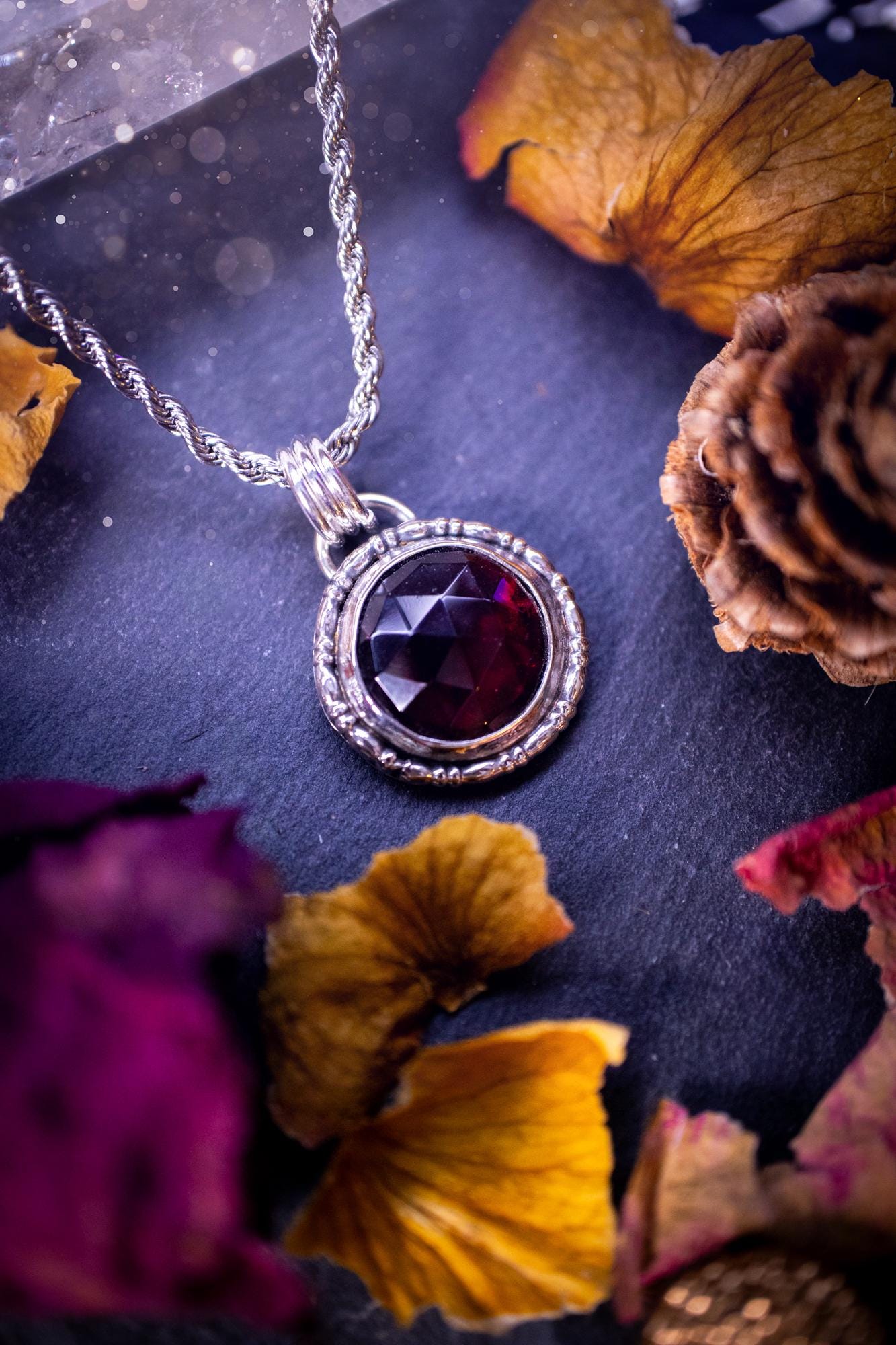 Handmade sterling silver pendant necklace featuring a circular design with a deep red garnet crystal centrepiece, showcasing a minimalist yet elegant artisan style. This piece has been created using recycled fine and sterling silver and features a gorgeous rose cut garnet that is full of sparkle. Suitable or special occasions such as birthdays, anniversaries, graduations and more. Garnet is the birthstone for January. Witchy and gothic handmade jewellery.