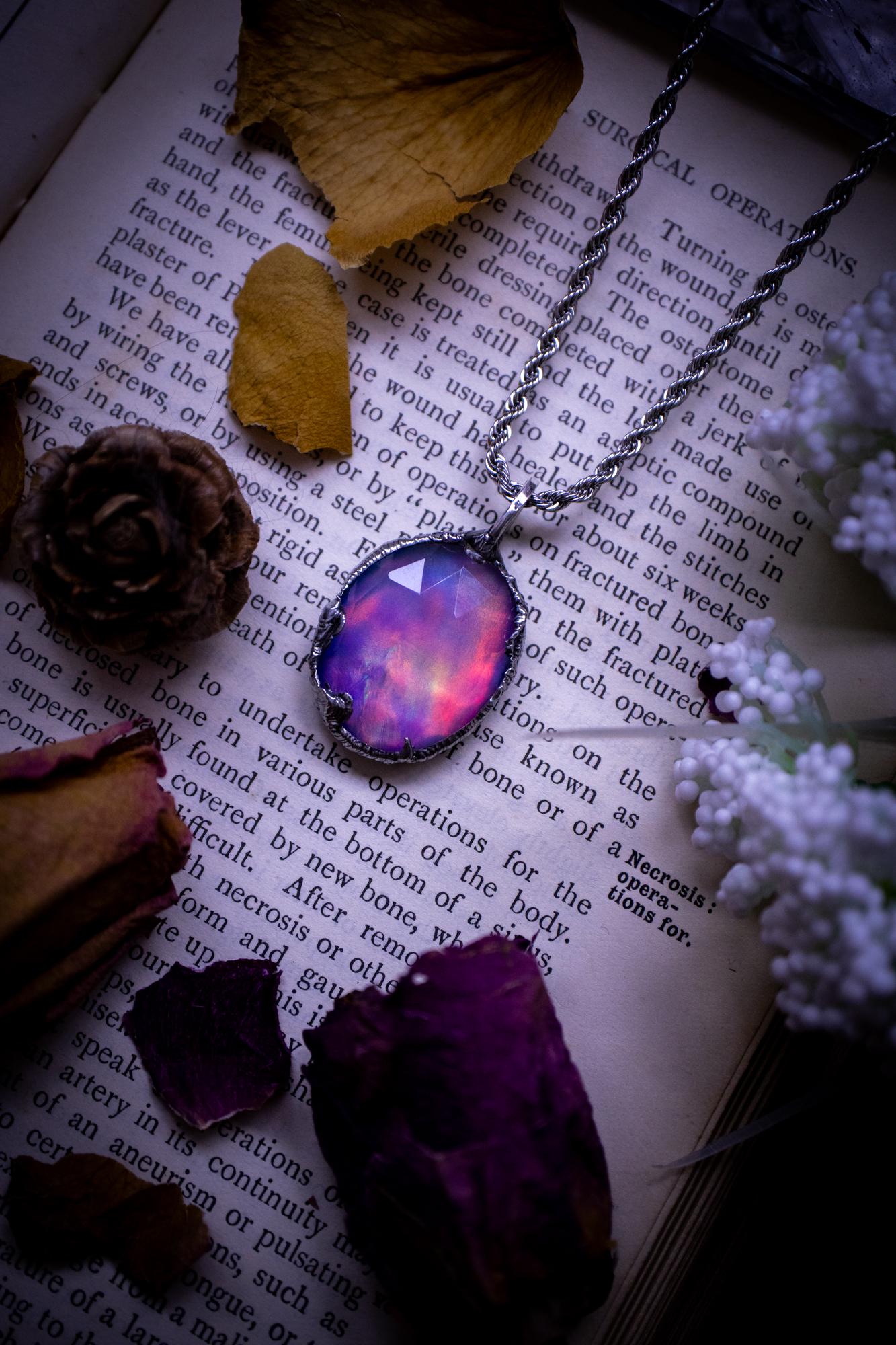 A beautiful, one of a kind, aurora opal pendant necklace. This little statement necklace is handmade using the tiffany technique, also known as soft soldering. Featuring the most stunning, and sparkly aurora opal which is full of pinks, greens and blues just like the northern lights. Aurora opals are man made opals that look similar to natural ones, they have a layer of rose quartz on top to give extra shine. The ideal gift for any crystal or jewellery lover. Gothic and witchy jewellery