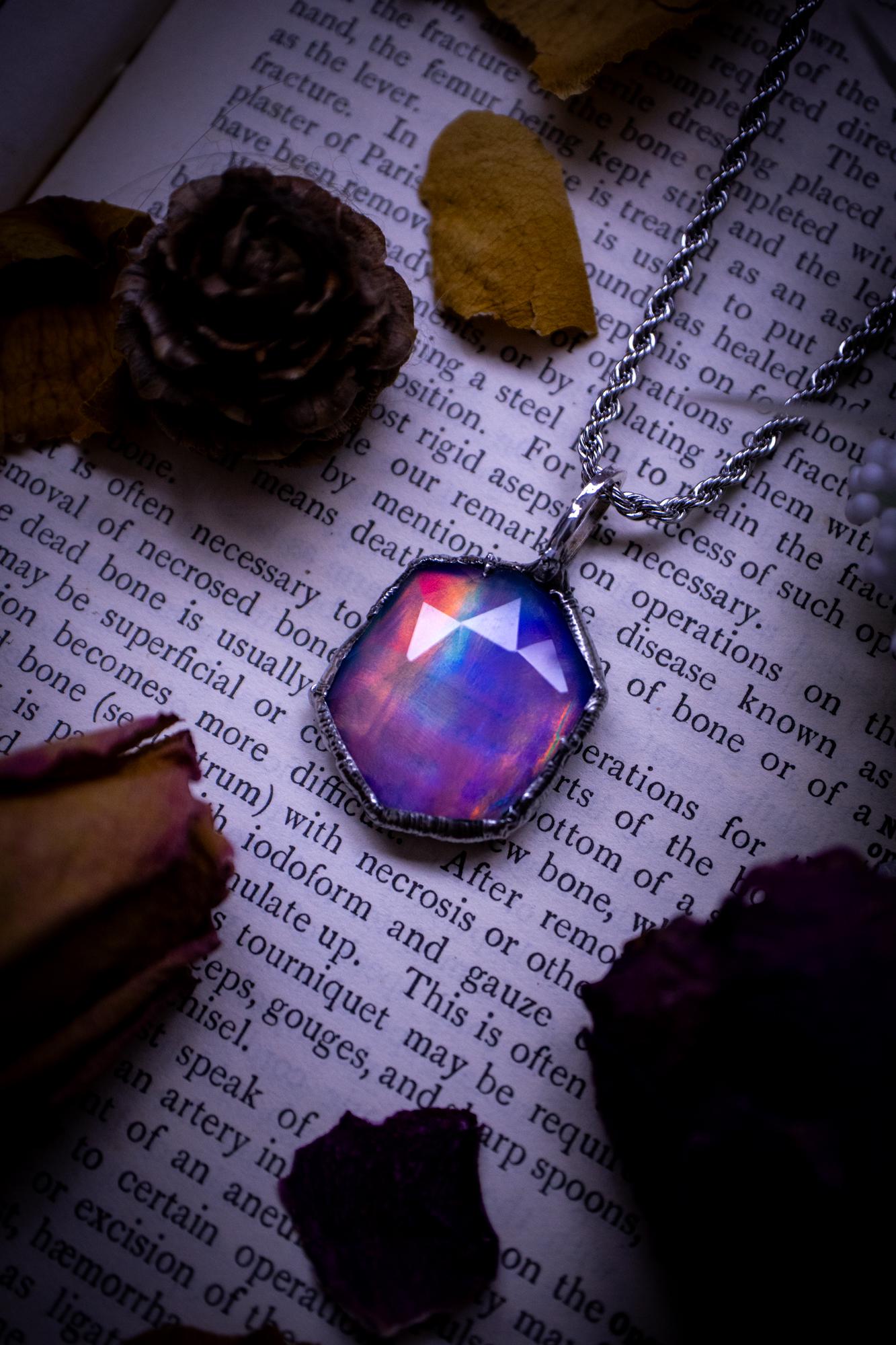 A beautiful, one of a kind, aurora opal pendant necklace. This little statement necklace is handmade using the tiffany technique, also known as soft soldering. Featuring the most stunning, and sparkly aurora opal which is full of pinks, greens and blues just like the northern lights. Aurora opals are man made opals that look similar to natural ones, they have a layer of rose quartz on top to give extra shine. The ideal gift for any crystal or jewellery lover. Gothic and witchy jewellery