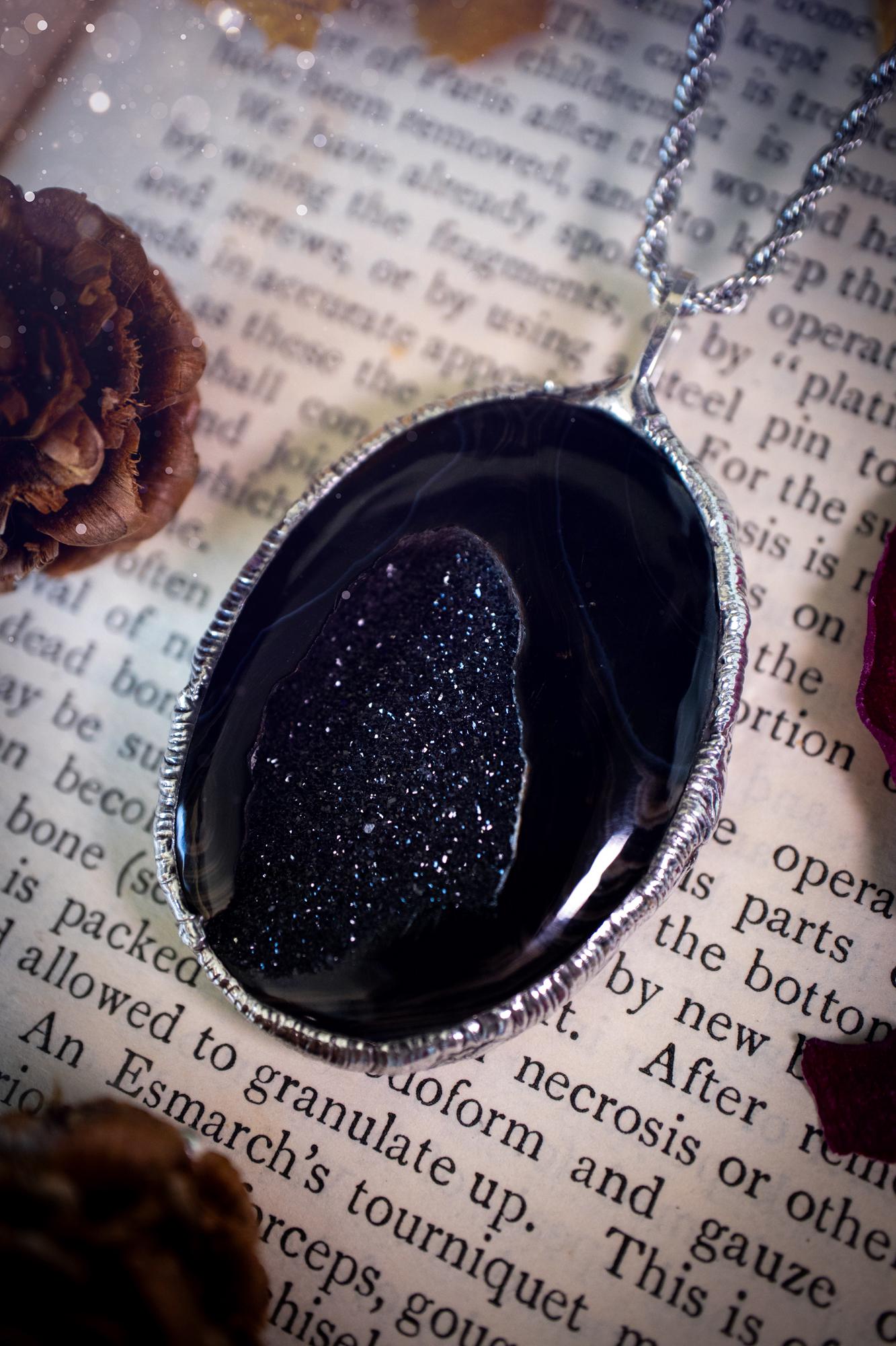 Beautiful and handcrafted, black druzy agate, crystal pendant necklace. This one of a kind piece of jewellery has been hand made using the tiffany technique, also known as soft soldering. The bezel is made with a solder that is lead free and contains elements of silver so when polished a high lustre is achieved. Featuring a large druzy agate with beautiful sparkle and banding. This is the ideal gift for any crystal or jewellery lover that likes a gothic and witchy vibe and aesthetic.