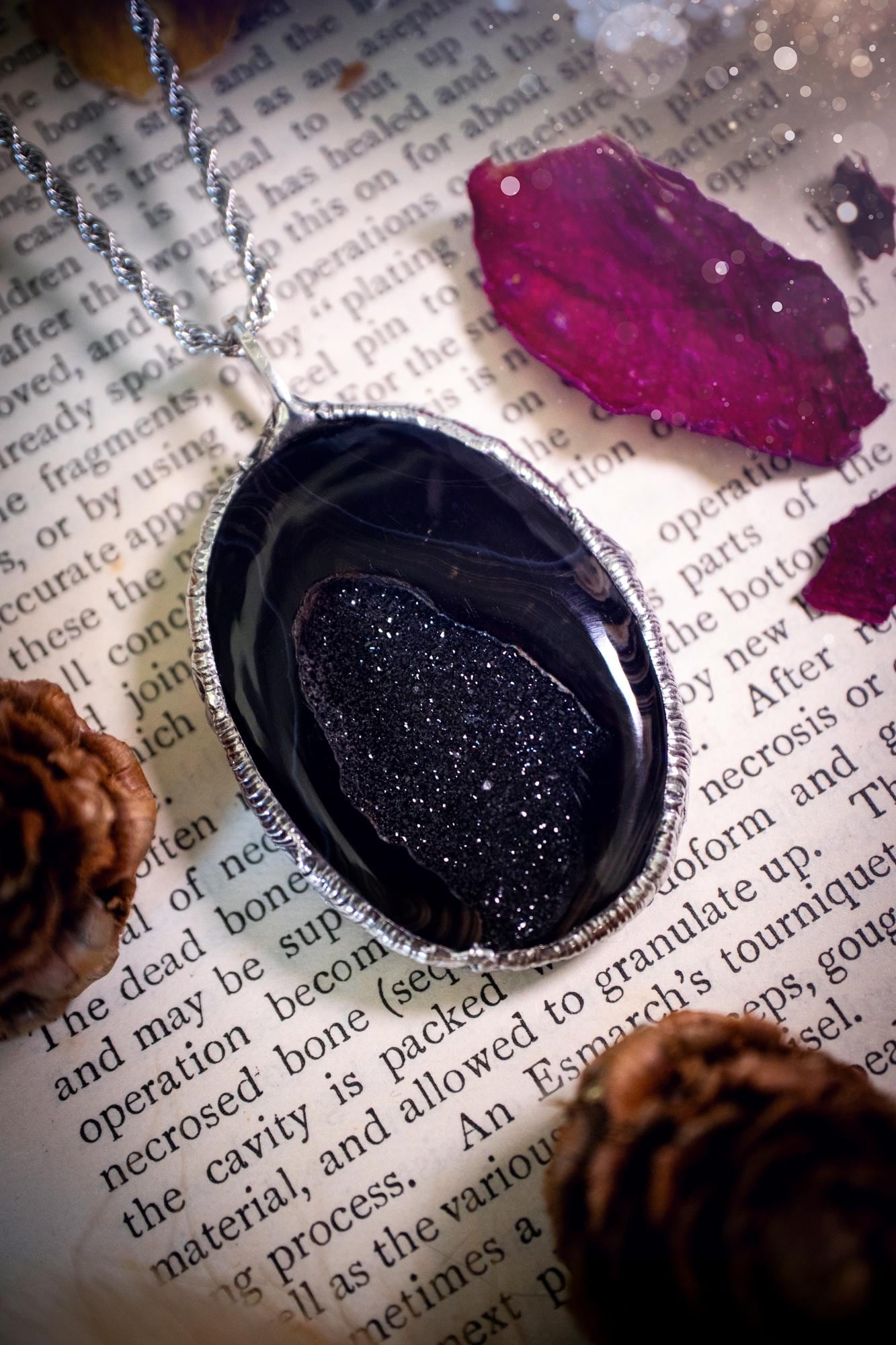 Beautiful and handcrafted, black druzy agate, crystal pendant necklace. This one of a kind piece of jewellery has been hand made using the tiffany technique, also known as soft soldering. The bezel is made with a solder that is lead free and contains elements of silver so when polished a high lustre is achieved. Featuring a large druzy agate with beautiful sparkle and banding. This is the ideal gift for any crystal or jewellery lover that likes a gothic and witchy vibe and aesthetic.