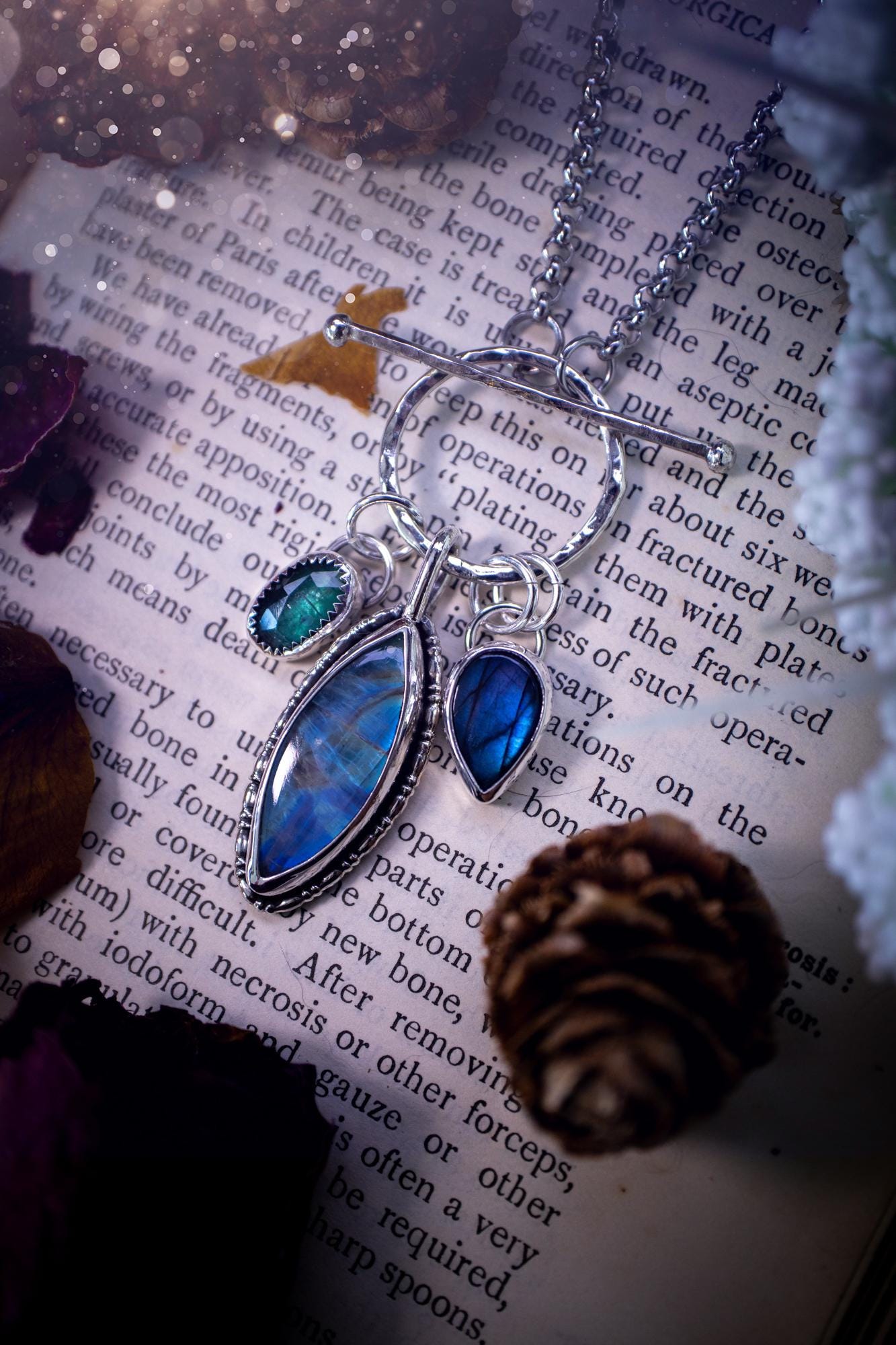 Beautiful and handmade, multi crystal charm pendant necklace. This stunning pendant necklace features a teal kyanite, a rainbow moonstone, and a purple labradorite crystal which hangs from a hammered toggle clasp. Made from a mix of fine and sterling silver, this necklace is very unique with all the beautiful crystals one could need! All crystals are natural and full of flash and vibrant colour. Ideal for any crystal or jewellery lover. Hippy, gothic and witchy jewellery.