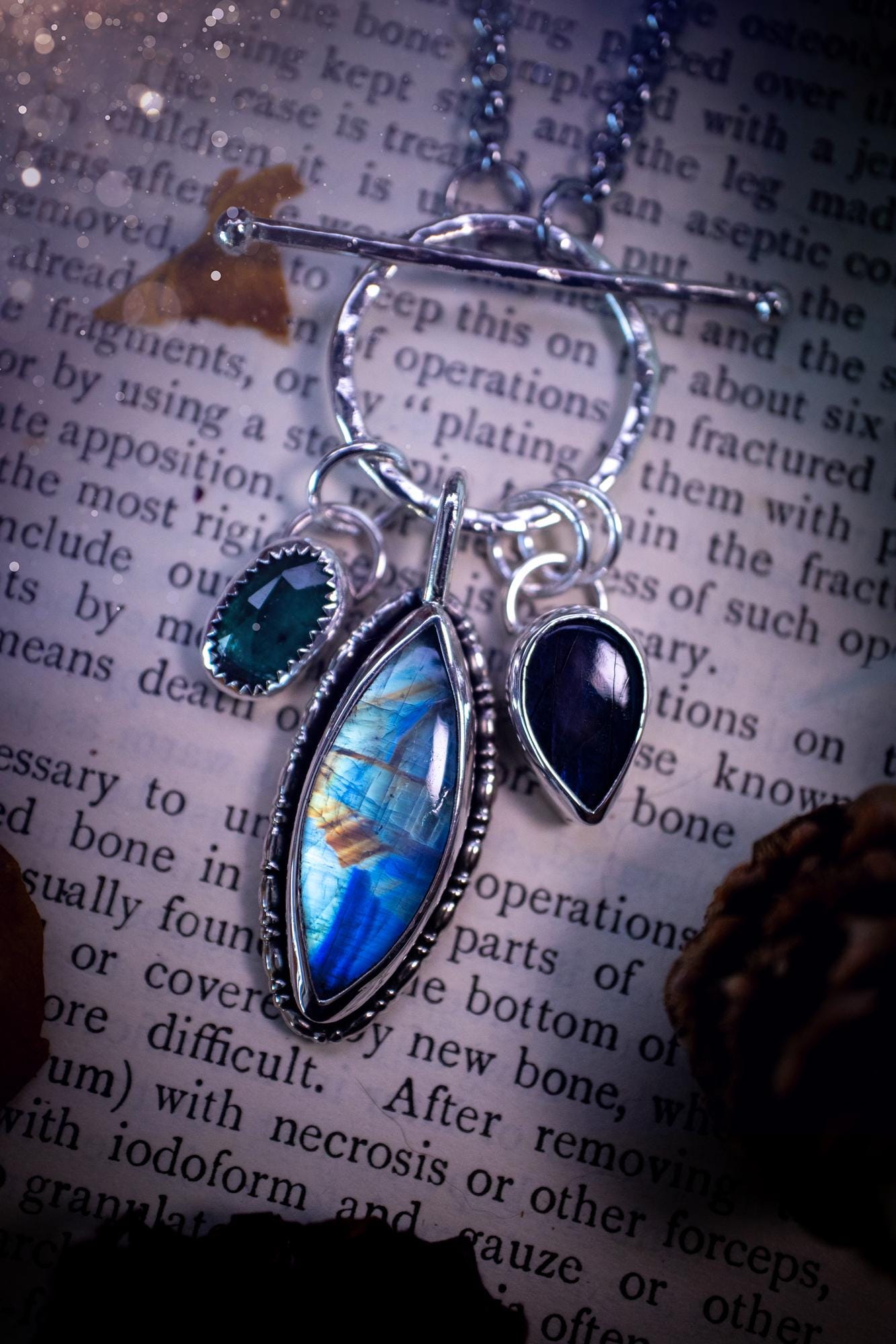 Beautiful and handmade, multi crystal charm pendant necklace. This stunning pendant necklace features a teal kyanite, a rainbow moonstone, and a purple labradorite crystal which hangs from a hammered toggle clasp. Made from a mix of fine and sterling silver, this necklace is very unique with all the beautiful crystals one could need! All crystals are natural and full of flash and vibrant colour. Ideal for any crystal or jewellery lover. Hippy, gothic and witchy jewellery.