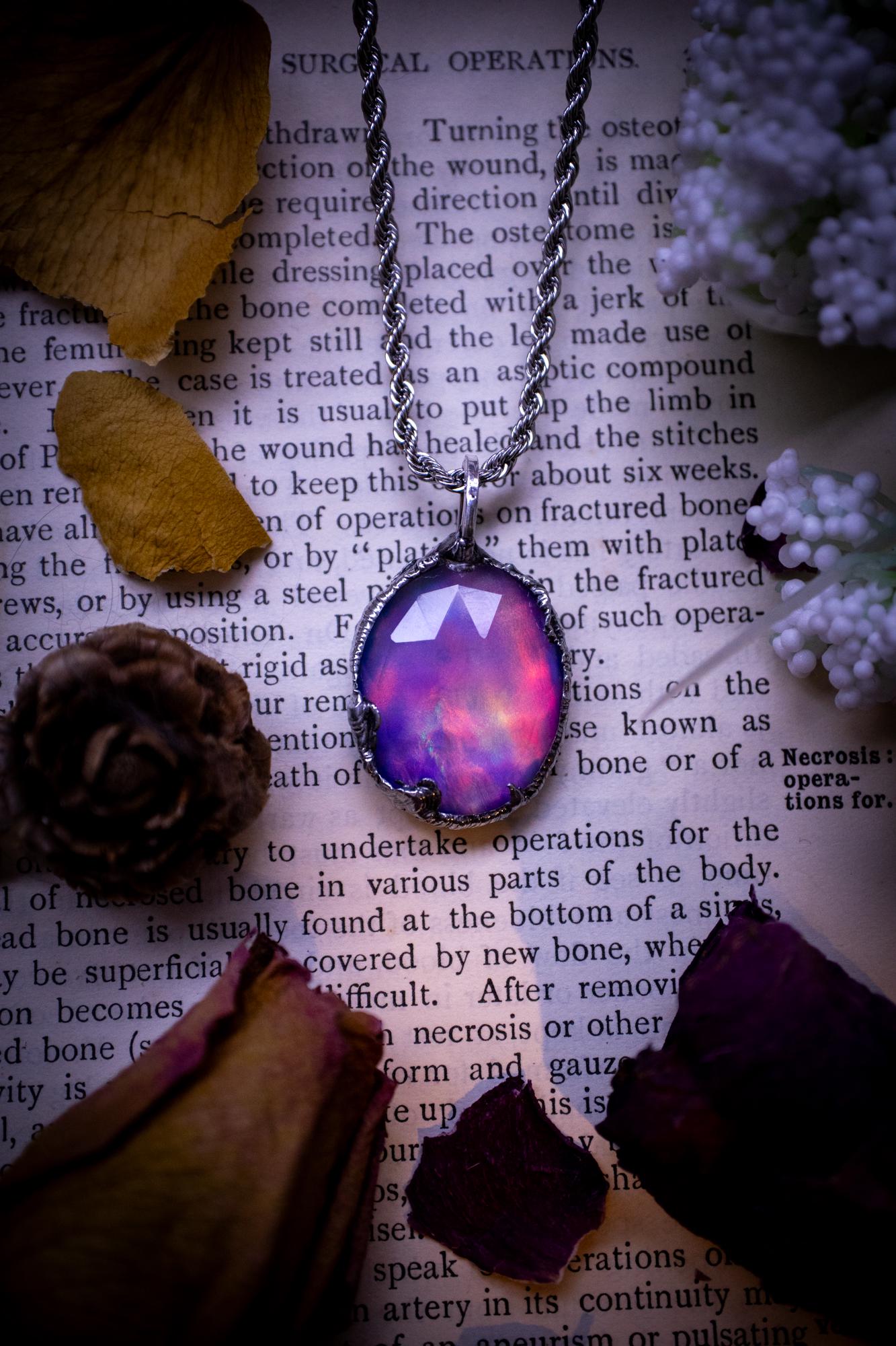 A beautiful, one of a kind, aurora opal pendant necklace. This little statement necklace is handmade using the tiffany technique, also known as soft soldering. Featuring the most stunning, and sparkly aurora opal which is full of pinks, greens and blues just like the northern lights. Aurora opals are man made opals that look similar to natural ones, they have a layer of rose quartz on top to give extra shine. The ideal gift for any crystal or jewellery lover. Gothic and witchy jewellery