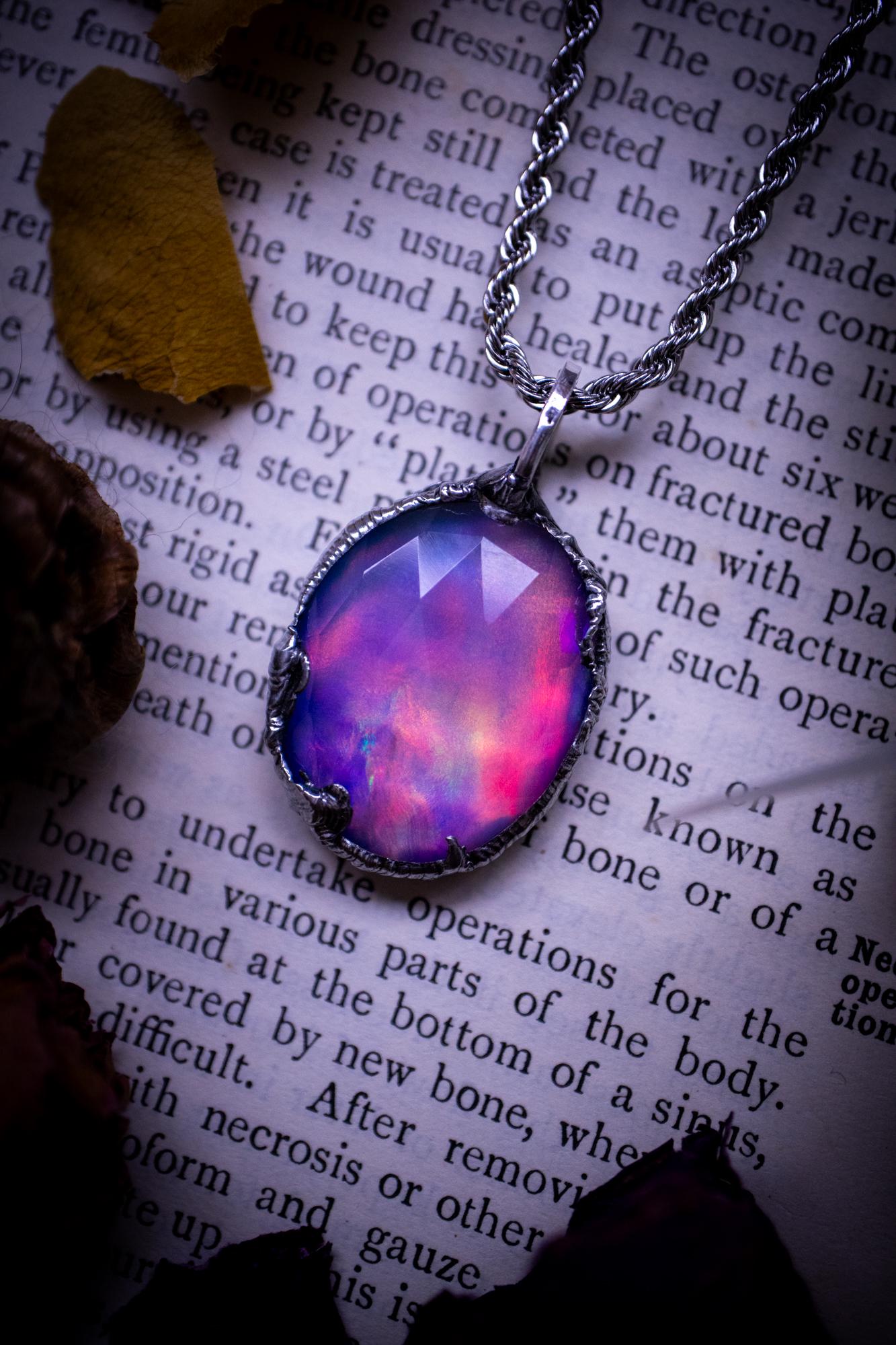 A beautiful, one of a kind, aurora opal pendant necklace. This little statement necklace is handmade using the tiffany technique, also known as soft soldering. Featuring the most stunning, and sparkly aurora opal which is full of pinks, greens and blues just like the northern lights. Aurora opals are man made opals that look similar to natural ones, they have a layer of rose quartz on top to give extra shine. The ideal gift for any crystal or jewellery lover. Gothic and witchy jewellery