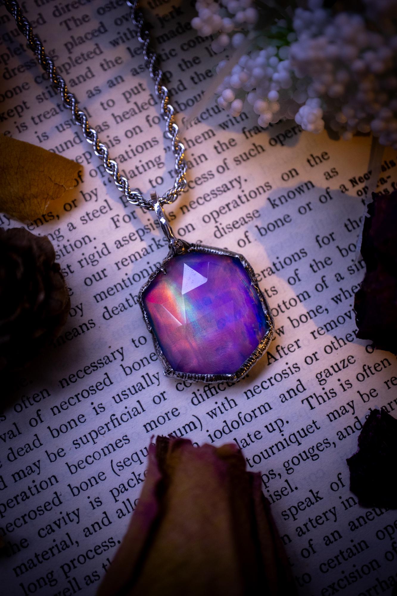 A beautiful, one of a kind, aurora opal pendant necklace. This little statement necklace is handmade using the tiffany technique, also known as soft soldering. Featuring the most stunning, and sparkly aurora opal which is full of pinks, greens and blues just like the northern lights. Aurora opals are man made opals that look similar to natural ones, they have a layer of rose quartz on top to give extra shine. The ideal gift for any crystal or jewellery lover. Gothic and witchy jewellery