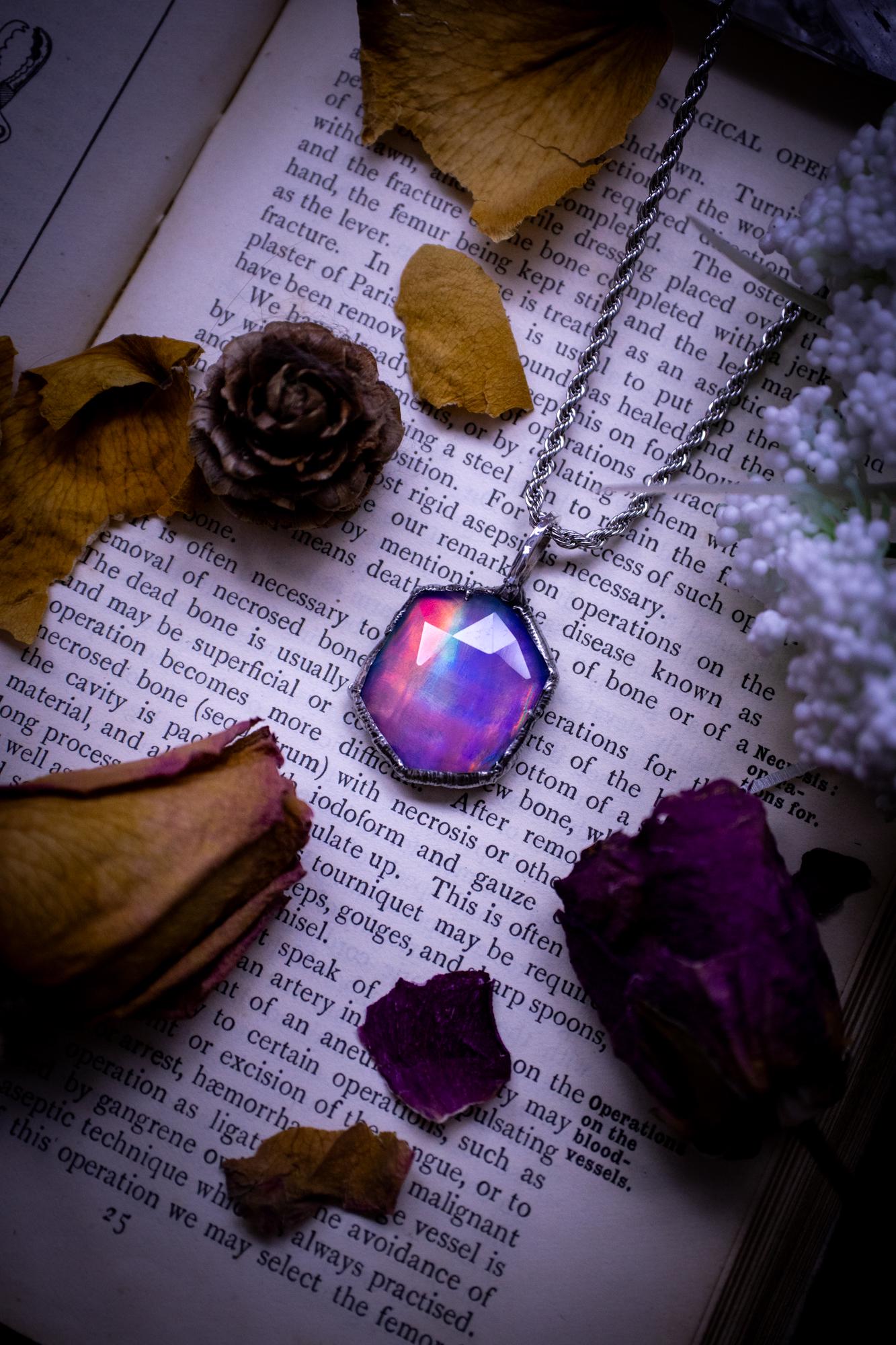 A beautiful, one of a kind, aurora opal pendant necklace. This little statement necklace is handmade using the tiffany technique, also known as soft soldering. Featuring the most stunning, and sparkly aurora opal which is full of pinks, greens and blues just like the northern lights. Aurora opals are man made opals that look similar to natural ones, they have a layer of rose quartz on top to give extra shine. The ideal gift for any crystal or jewellery lover. Gothic and witchy jewellery