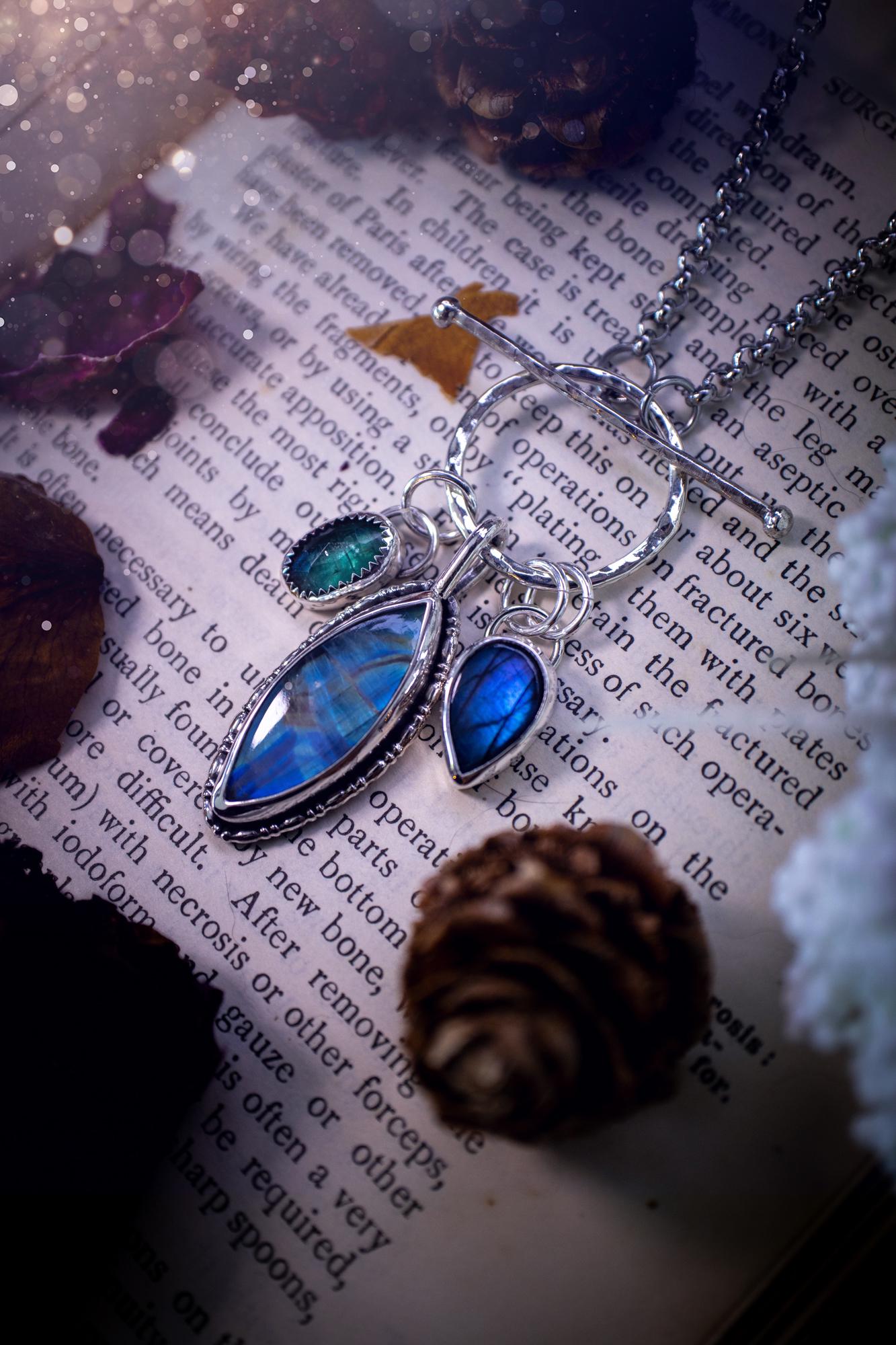 Beautiful and handmade, multi crystal charm pendant necklace. This stunning pendant necklace features a teal kyanite, a rainbow moonstone, and a purple labradorite crystal which hangs from a hammered toggle clasp. Made from a mix of fine and sterling silver, this necklace is very unique with all the beautiful crystals one could need! All crystals are natural and full of flash and vibrant colour. Ideal for any crystal or jewellery lover. Hippy, gothic and witchy jewellery.