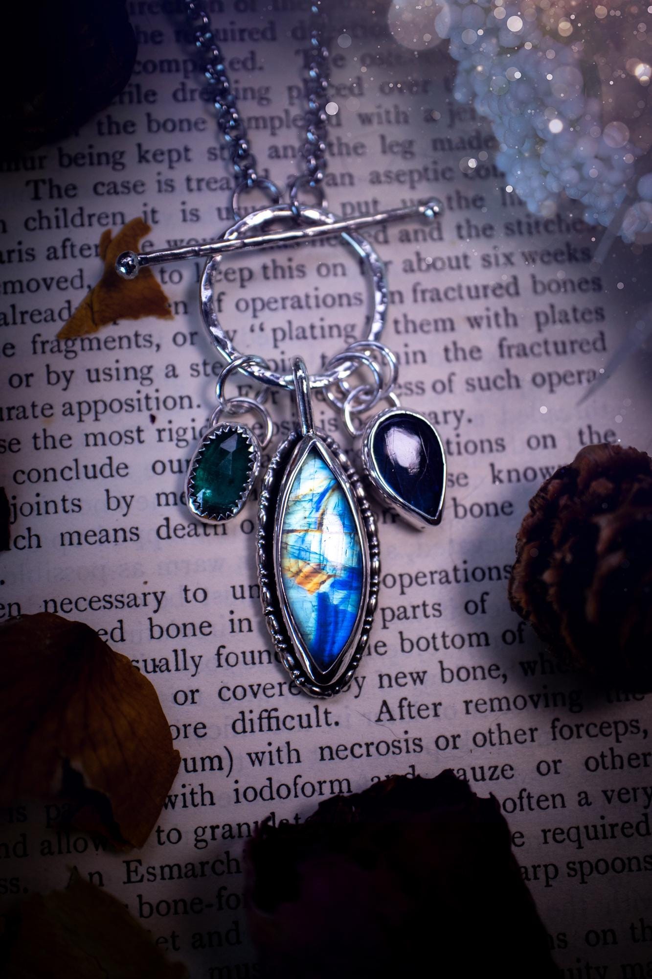 Beautiful and handmade, multi crystal charm pendant necklace. This stunning pendant necklace features a teal kyanite, a rainbow moonstone, and a purple labradorite crystal which hangs from a hammered toggle clasp. Made from a mix of fine and sterling silver, this necklace is very unique with all the beautiful crystals one could need! All crystals are natural and full of flash and vibrant colour. Ideal for any crystal or jewellery lover. Hippy, gothic and witchy jewellery.