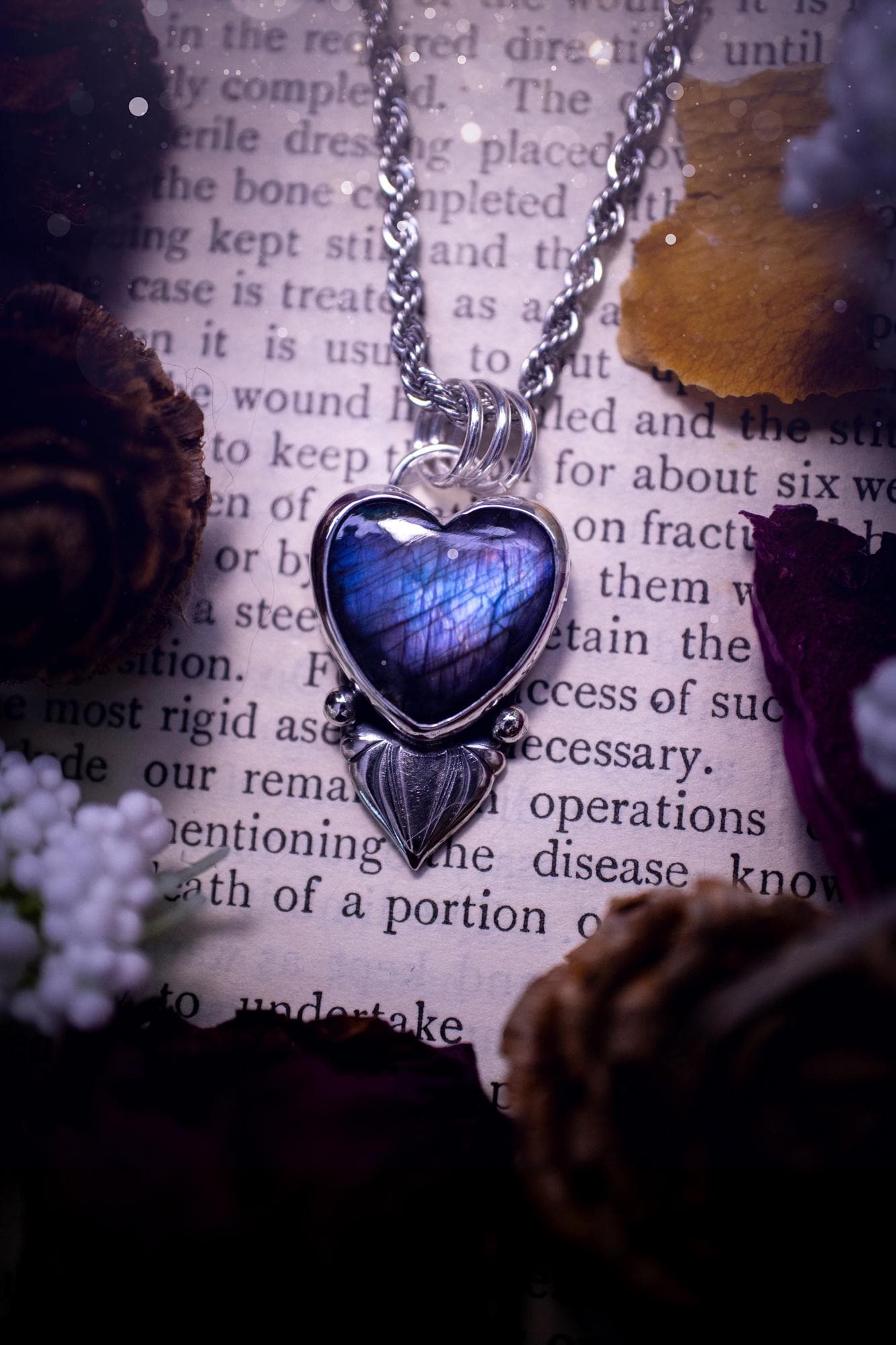 Stunning and handmade, all natural, purple and blue, labradorite crystal heart pendant necklace. This pendant necklace has been handmade from fine and sterling silver. Featuring the most beautiful labradorite heart crystal that is full of bold purples, deep blues and a shimmer of silver. Accompanying the crystal gemstone is fan and ball silver components giving this piece its own uniqueness. This piece of jewellery would be ideal for any crystal or jewellery lover and gives off gothic vibes.