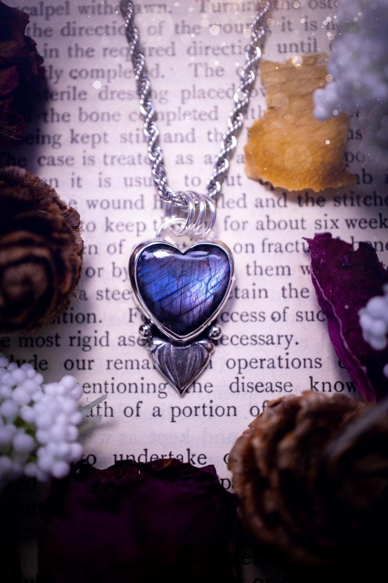 Stunning and handmade, all natural, purple and blue, labradorite crystal heart pendant necklace. This pendant necklace has been handmade from fine and sterling silver. Featuring the most beautiful labradorite heart crystal that is full of bold purples, deep blues and a shimmer of silver. Accompanying the crystal gemstone is fan and ball silver components giving this piece its own uniqueness. This piece of jewellery would be ideal for any crystal or jewellery lover and gives off gothic vibes.