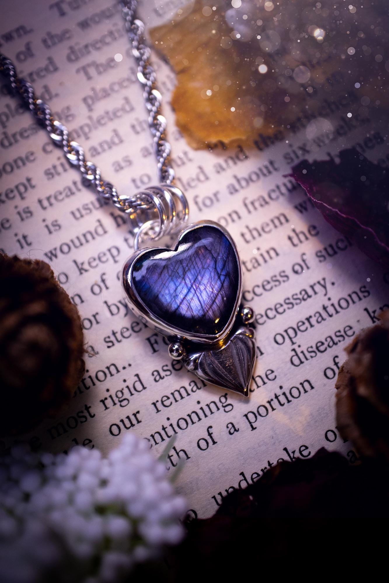 Stunning and handmade, all natural, purple and blue, labradorite crystal heart pendant necklace. This pendant necklace has been handmade from fine and sterling silver. Featuring the most beautiful labradorite heart crystal that is full of bold purples, deep blues and a shimmer of silver. Accompanying the crystal gemstone is fan and ball silver components giving this piece its own uniqueness. This piece of jewellery would be ideal for any crystal or jewellery lover and gives off gothic vibes.