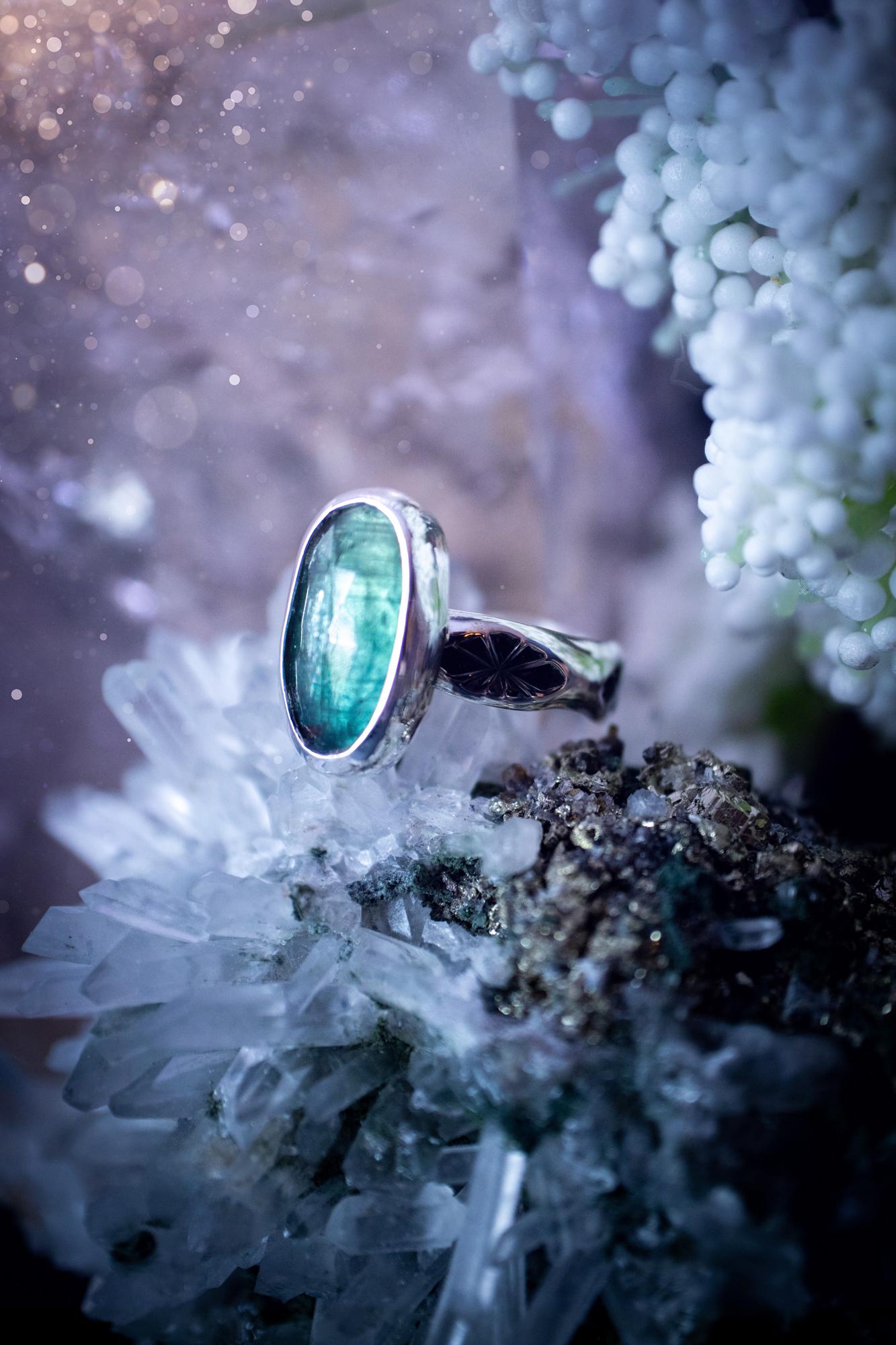 Beautiful and handcrafted, natural teal green kyanite crystal, staking ring. This stunning ring has been hand made using fine and sterling silver. It features a beautiful and natural teal green kyanite crystal that has rainbows and flash, such a gorgeous colour. The ring shank on this ring has been stamped with a gothic pattern to give it a one of a kind vibe. Ideal gift for that special person in your life, or for any crystal and jewellery lover. Hippy, witchy and gothic jewellery for the soul.