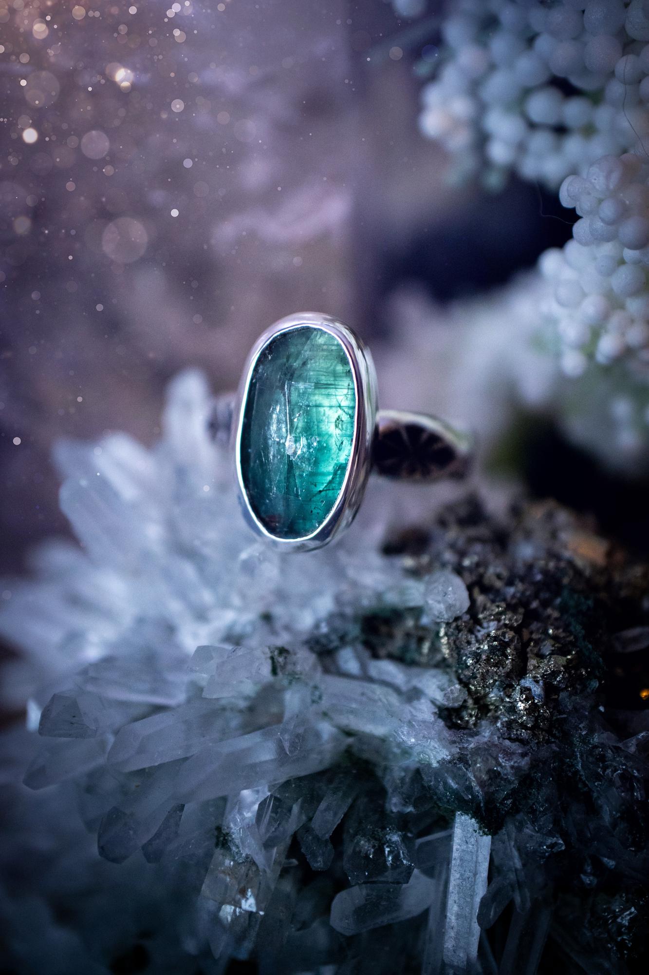 Beautiful and handcrafted, natural teal green kyanite crystal, staking ring. This stunning ring has been hand made using fine and sterling silver. It features a beautiful and natural teal green kyanite crystal that has rainbows and flash, such a gorgeous colour. The ring shank on this ring has been stamped with a gothic pattern to give it a one of a kind vibe. Ideal gift for that special person in your life, or for any crystal and jewellery lover. Hippy, witchy and gothic jewellery for the soul.