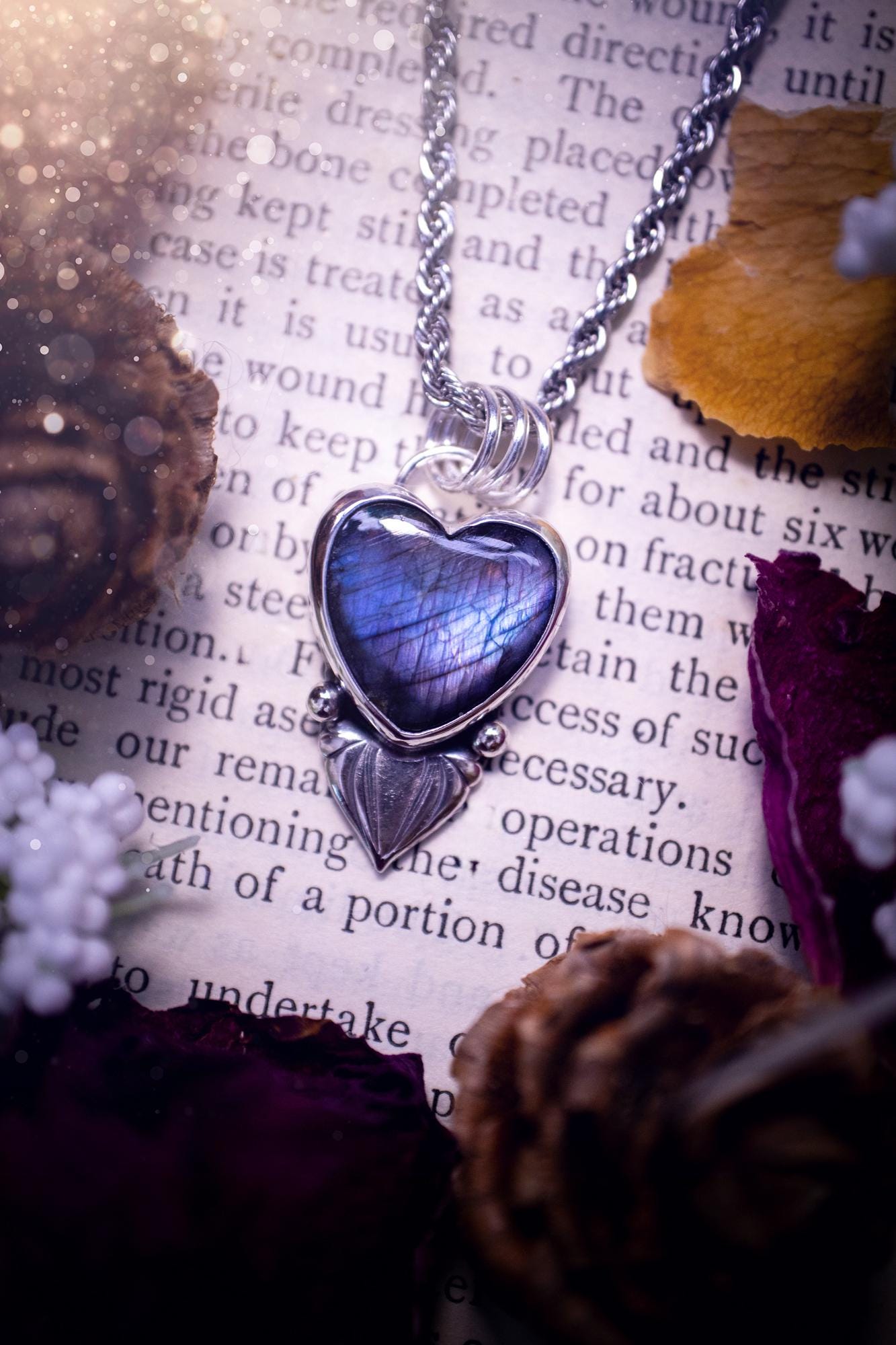 Stunning and handmade, all natural, purple and blue, labradorite crystal heart pendant necklace. This pendant necklace has been handmade from fine and sterling silver. Featuring the most beautiful labradorite heart crystal that is full of bold purples, deep blues and a shimmer of silver. Accompanying the crystal gemstone is fan and ball silver components giving this piece its own uniqueness. This piece of jewellery would be ideal for any crystal or jewellery lover and gives off gothic vibes.