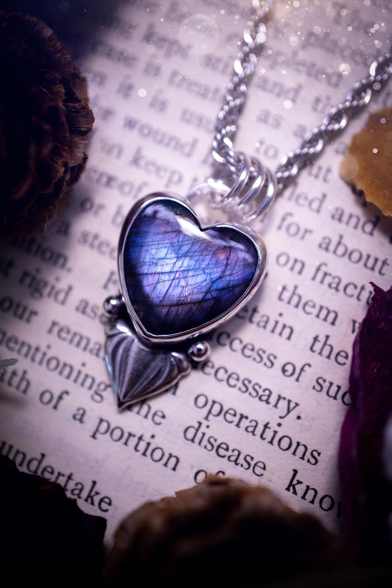 Stunning and handmade, all natural, purple and blue, labradorite crystal heart pendant necklace. This pendant necklace has been handmade from fine and sterling silver. Featuring the most beautiful labradorite heart crystal that is full of bold purples, deep blues and a shimmer of silver. Accompanying the crystal gemstone is fan and ball silver components giving this piece its own uniqueness. This piece of jewellery would be ideal for any crystal or jewellery lover and gives off gothic vibes.