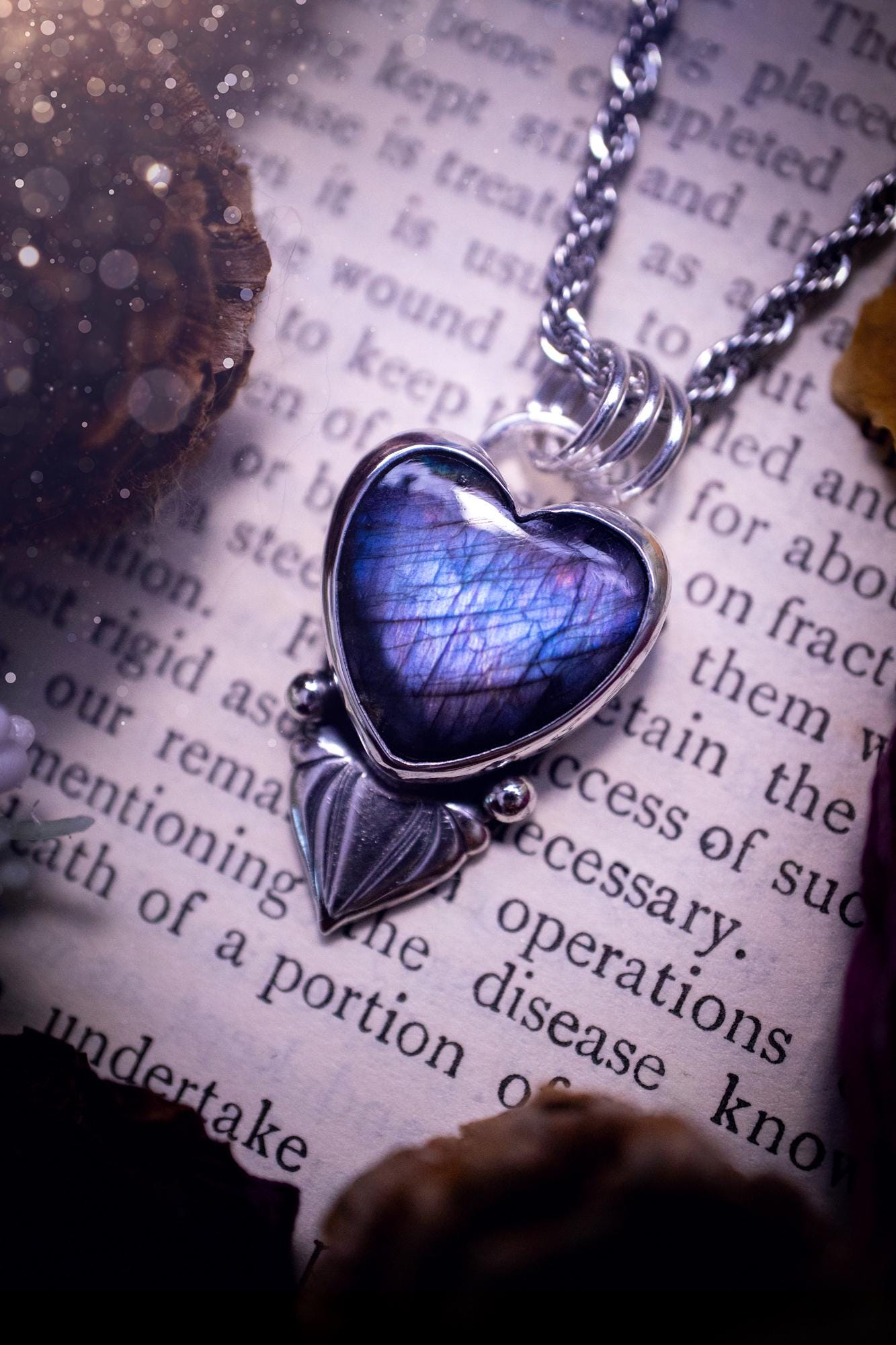 Stunning and handmade, all natural, purple and blue, labradorite crystal heart pendant necklace. This pendant necklace has been handmade from fine and sterling silver. Featuring the most beautiful labradorite heart crystal that is full of bold purples, deep blues and a shimmer of silver. Accompanying the crystal gemstone is fan and ball silver components giving this piece its own uniqueness. This piece of jewellery would be ideal for any crystal or jewellery lover and gives off gothic vibes.