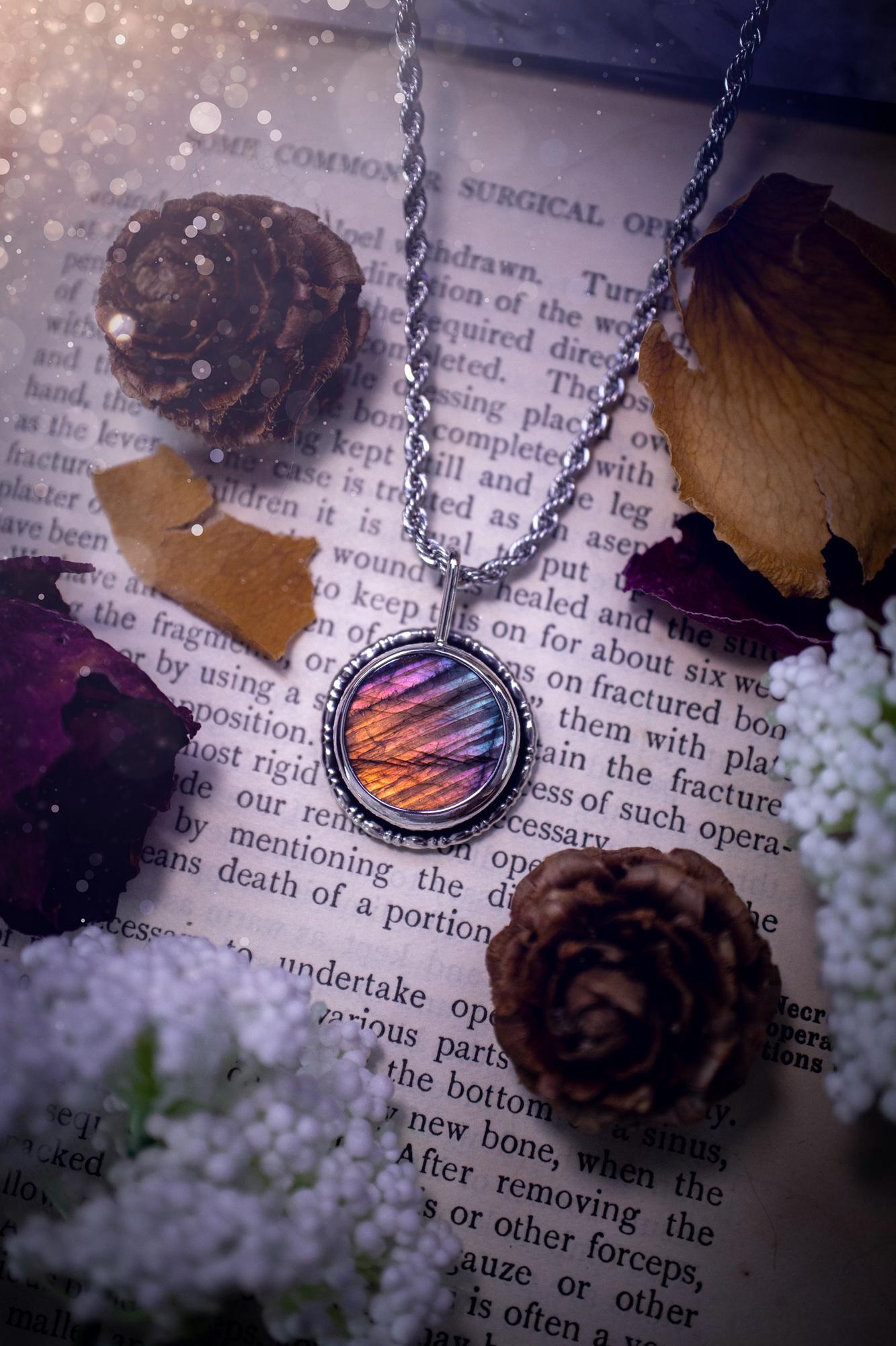Beautiful and handcrafted, natural rainbow, pink, purple, and silver labradorite spectrolite pendant necklace. This beautiful pendant has been handmade using recycled fine and sterling silver. Featuring a round labradorite that is full of natural pinks, purples and silver hues. Around the crystal is a smooth inner bezel with gallery wire around as the outer bezel. This is the ideal piece of jewellery for a loved one or to treat yourself. Suitable for crystal and jewellery lovers. Gothic vibes.