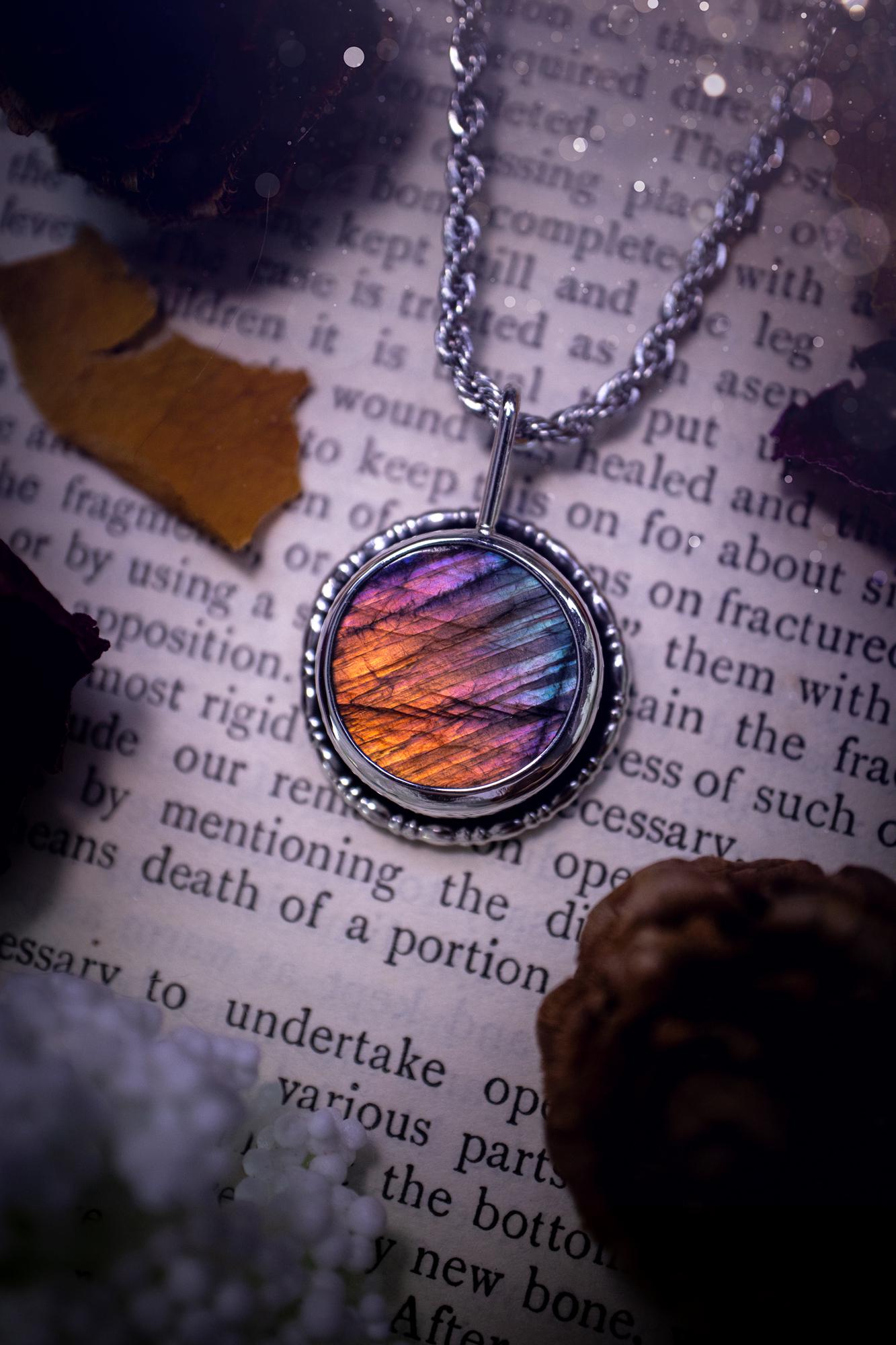 Beautiful and handcrafted, natural rainbow, pink, purple, and silver labradorite spectrolite pendant necklace. This beautiful pendant has been handmade using recycled fine and sterling silver. Featuring a round labradorite that is full of natural pinks, purples and silver hues. Around the crystal is a smooth inner bezel with gallery wire around as the outer bezel. This is the ideal piece of jewellery for a loved one or to treat yourself. Suitable for crystal and jewellery lovers. Gothic vibes.