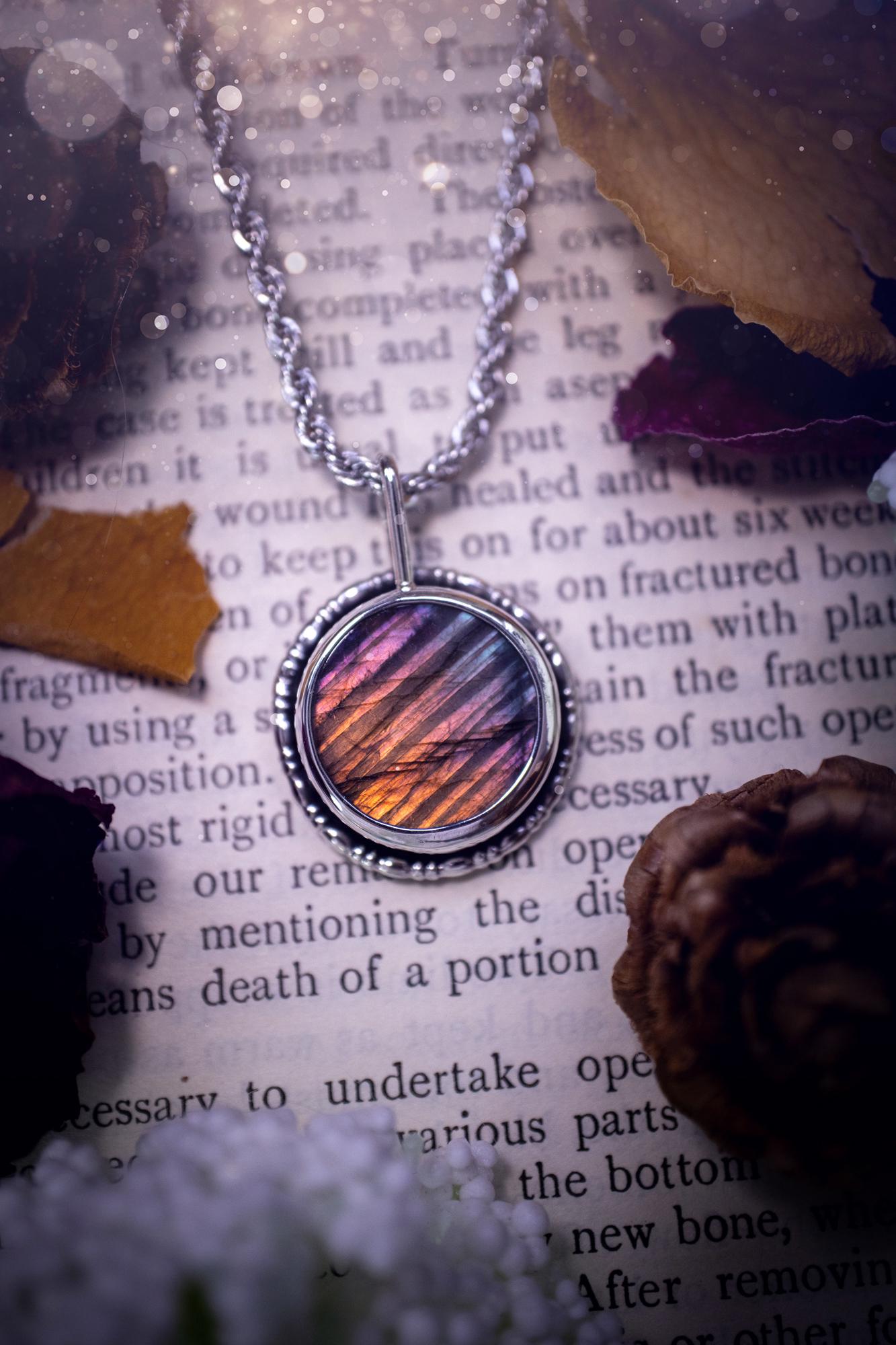 Beautiful and handcrafted, natural rainbow, pink, purple, and silver labradorite spectrolite pendant necklace. This beautiful pendant has been handmade using recycled fine and sterling silver. Featuring a round labradorite that is full of natural pinks, purples and silver hues. Around the crystal is a smooth inner bezel with gallery wire around as the outer bezel. This is the ideal piece of jewellery for a loved one or to treat yourself. Suitable for crystal and jewellery lovers. Gothic vibes.