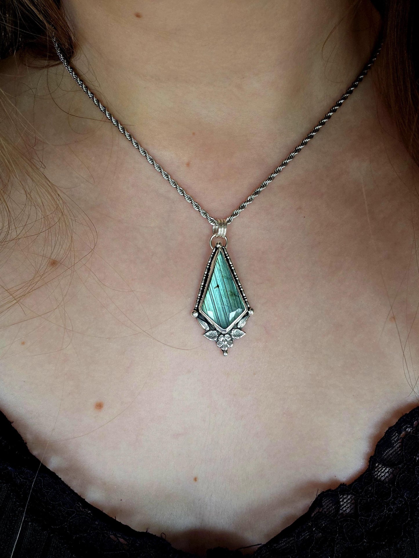 This stunning pendant necklace has been handcrafted using a mix of recycled fine and sterling silver. Featuring a beautiful and natural green and blue hued labradorite crystal that is full of flash! accompanying this magical crystal is a mix of fae inspired components such as little leaves, flower, silver balls and gothic gallery wire. A true bespoke piece with no other being the same! Ideal for any crystal and jewellery lover that loves a witchy and gothic vibe, along with the beauty of nature!