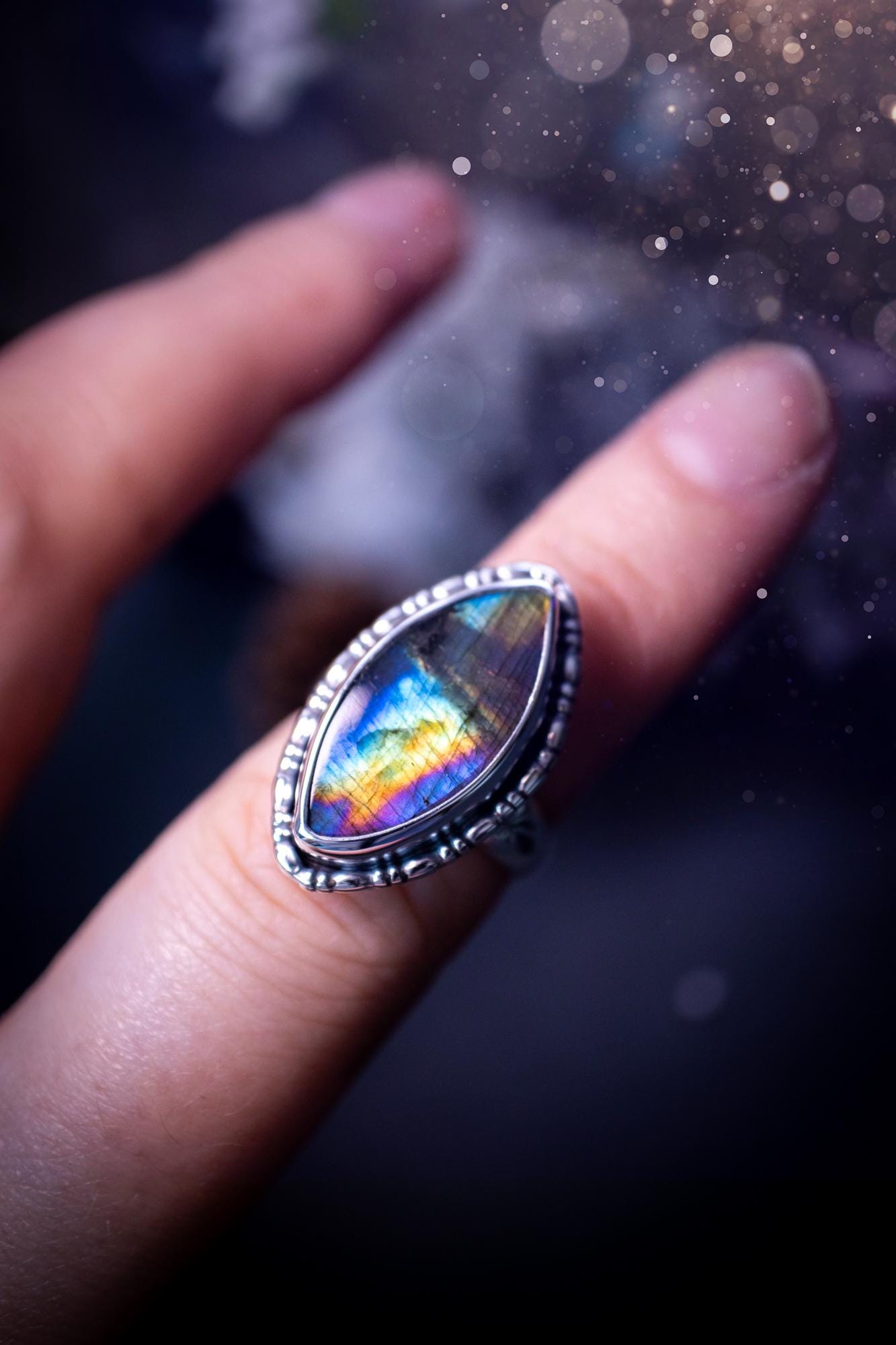 Handcrafted sterling silver statement ring featuring a stunning spectrolite labradorite crystal with vibrant flashes of purple, yellow, and blue. This magical gemstone shimmers with an ethereal glow, making it a captivating piece for any jewellery collection. Ideal for crystal lovers, spiritual souls, and those drawn to unique, one-of-a-kind designs. A bold, mystical accessory perfect for expressing your inner light and energy. Gothic and handmade jewellery gifts, ideal for crystal lovers.