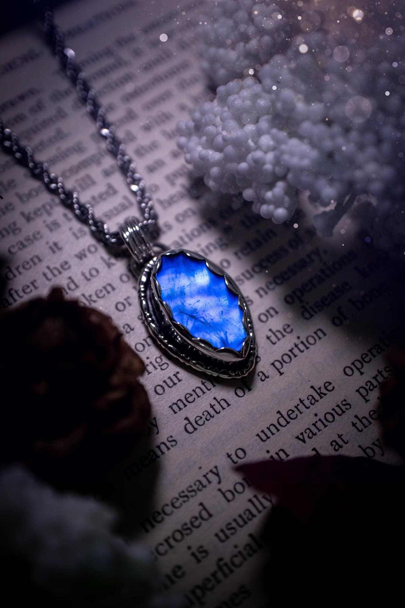 A handmade rainbow moonstone pendant necklace featuring a glowing, iridescent moonstone with blue and purple flashes. The stone is set in a scallop bezel, framed by bespoke gothic gallery wire that adds both hippy and witchy vibes. Crafted from sterling and fine silver, the pendant hangs on a silver chain, exuding mystical charm and alternative style. A one-of-a-kind piece with gothic, and magical energy. The ideal gift for crystal and jewellery lovers. Moonstone is the birthstone for June.