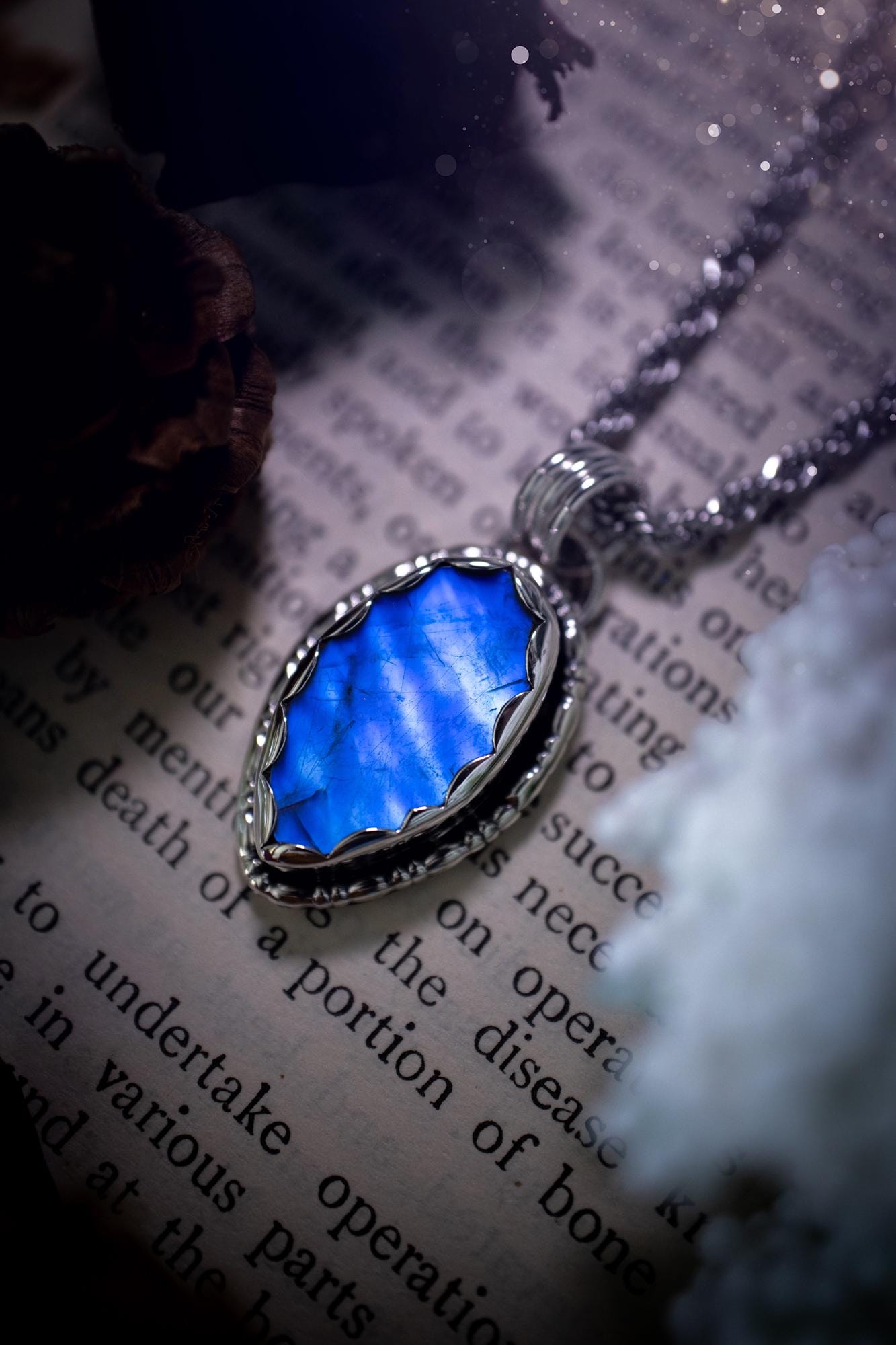 A handmade rainbow moonstone pendant necklace featuring a glowing, iridescent moonstone with blue and purple flashes. The stone is set in a scallop bezel, framed by bespoke gothic gallery wire that adds both hippy and witchy vibes. Crafted from sterling and fine silver, the pendant hangs on a silver chain, exuding mystical charm and alternative style. A one-of-a-kind piece with gothic, and magical energy. The ideal gift for crystal and jewellery lovers. Moonstone is the birthstone for June.