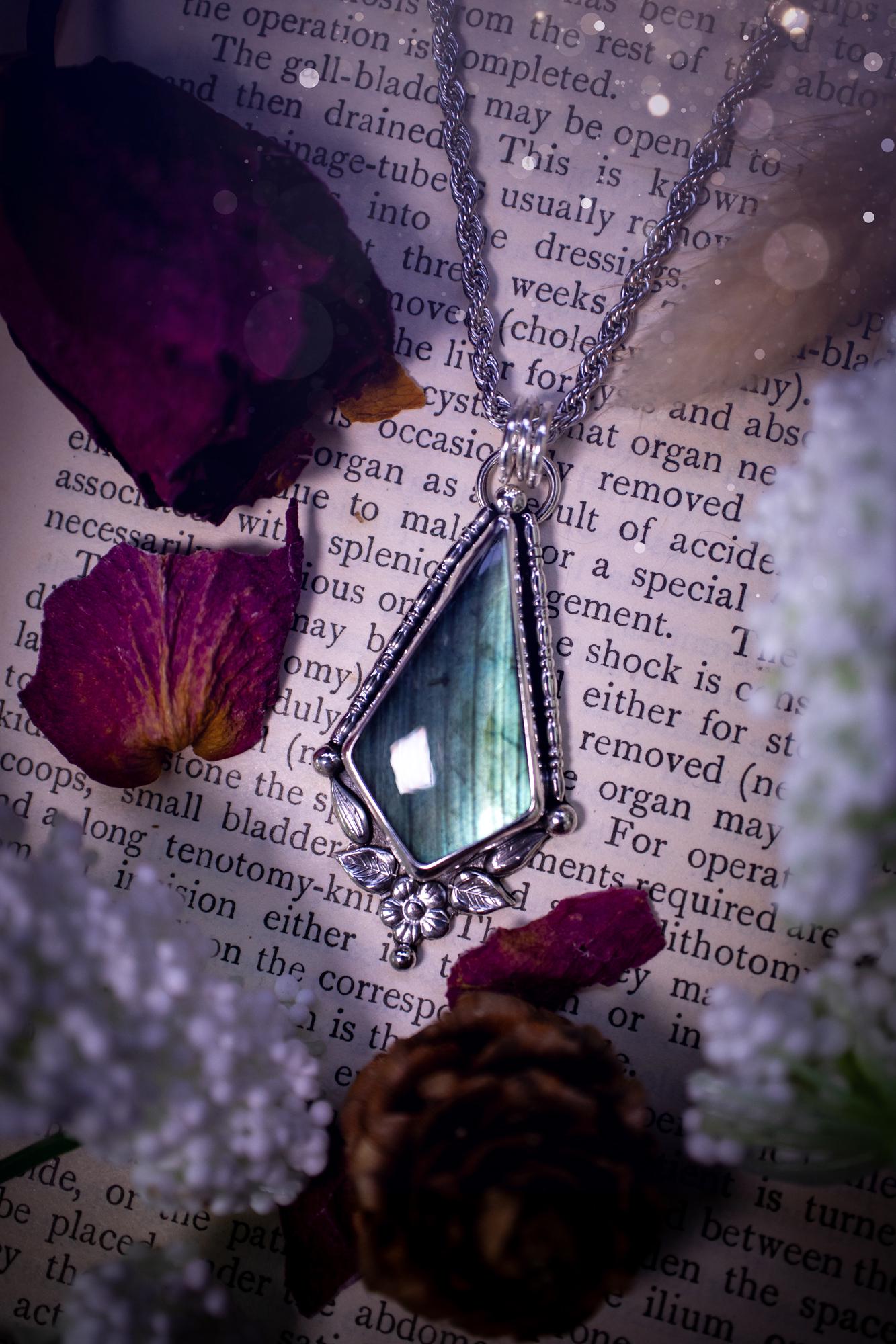 This stunning pendant necklace has been handcrafted using a mix of recycled fine and sterling silver. Featuring a beautiful and natural green and blue hued labradorite crystal that is full of flash! accompanying this magical crystal is a mix of fae inspired components such as little leaves, flower, silver balls and gothic gallery wire. A true bespoke piece with no other being the same! Ideal for any crystal and jewellery lover that loves a witchy and gothic vibe, along with the beauty of nature!