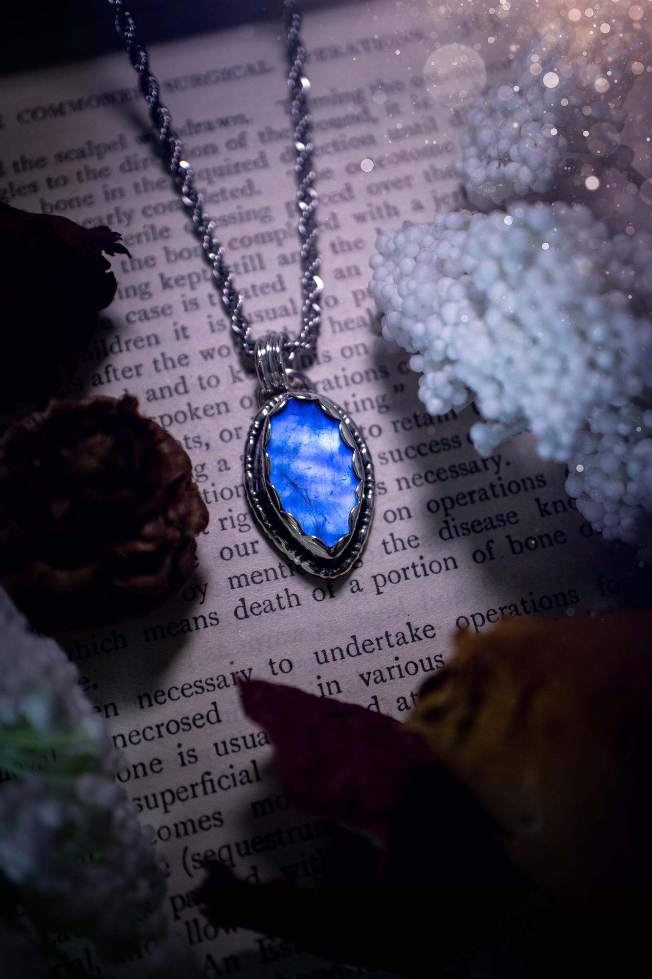 A handmade rainbow moonstone pendant necklace featuring a glowing, iridescent moonstone with blue and purple flashes. The stone is set in a scallop bezel, framed by bespoke gothic gallery wire that adds both hippy and witchy vibes. Crafted from sterling and fine silver, the pendant hangs on a silver chain, exuding mystical charm and alternative style. A one-of-a-kind piece with gothic, and magical energy. The ideal gift for crystal and jewellery lovers. Moonstone is the birthstone for June.