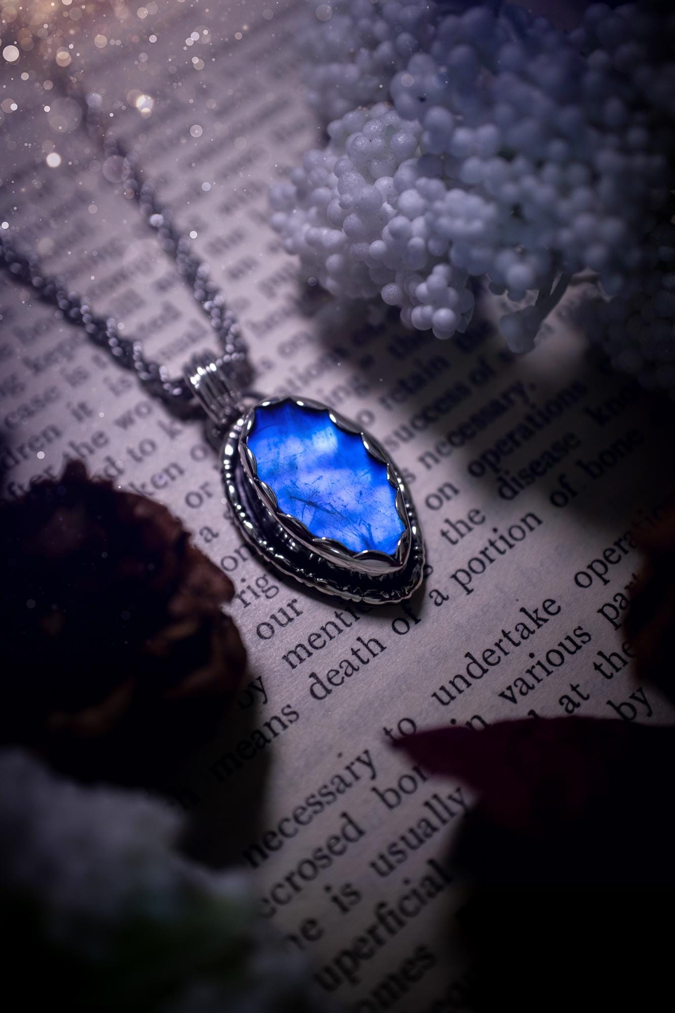A handmade rainbow moonstone pendant necklace featuring a glowing, iridescent moonstone with blue and purple flashes. The stone is set in a scallop bezel, framed by bespoke gothic gallery wire that adds both hippy and witchy vibes. Crafted from sterling and fine silver, the pendant hangs on a silver chain, exuding mystical charm and alternative style. A one-of-a-kind piece with gothic, and magical energy. The ideal gift for crystal and jewellery lovers. Moonstone is the birthstone for June.