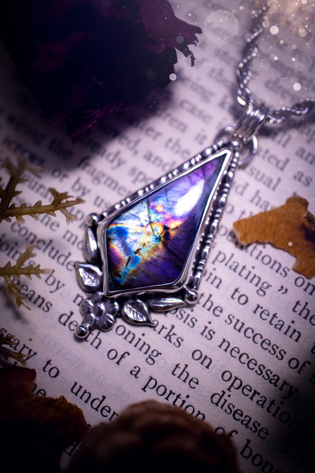 This stunning pendant necklace has been handcrafted using a mix of recycled fine and sterling silver. Featuring a beautiful and natural purple and pink hued labradorite crystal that is full of flash! accompanying this magical crystal is a mix of fae inspired components such as little leaves, flower, silver balls and gothic gallery wire. A true bespoke piece with no other being the same! Ideal for any crystal and jewellery lover that loves a witchy and gothic vibe, along with the beauty of nature