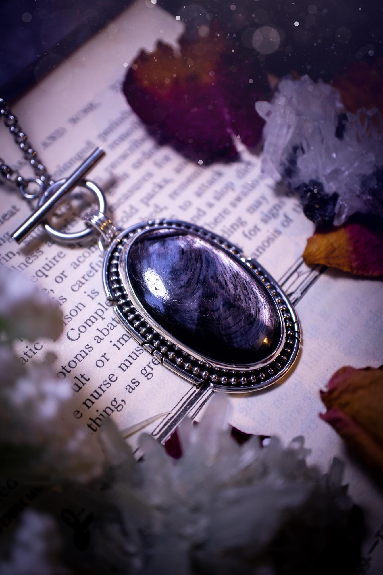 Beautifully handmade, amulet pendant necklace which features the most beautiful, flashy hypersthene crystal gemstone. This pendant has been handcrafted using a mix of fine and sterling silver. It features a smooth bezel with beaded, and hand carved smooth wire around the stone making this piece totally bespoke and one of a kind. The hypersthene has an array of beautiful greys and blacks. This pendant would be suitable for any crystal and jewellery lover, full of gothic and witchy vibes.