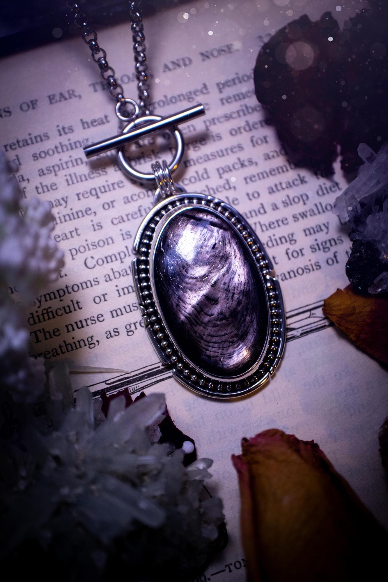 Beautifully handmade, amulet pendant necklace which features the most beautiful, flashy hypersthene crystal gemstone. This pendant has been handcrafted using a mix of fine and sterling silver. It features a smooth bezel with beaded, and hand carved smooth wire around the stone making this piece totally bespoke and one of a kind. The hypersthene has an array of beautiful greys and blacks. This pendant would be suitable for any crystal and jewellery lover, full of gothic and witchy vibes.