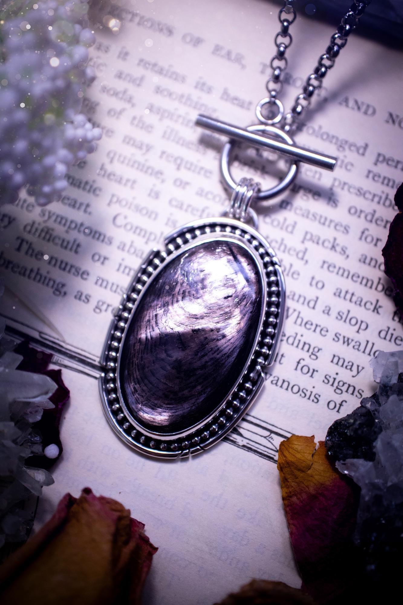 Beautifully handmade, amulet pendant necklace which features the most beautiful, flashy hypersthene crystal gemstone. This pendant has been handcrafted using a mix of fine and sterling silver. It features a smooth bezel with beaded, and hand carved smooth wire around the stone making this piece totally bespoke and one of a kind. The hypersthene has an array of beautiful greys and blacks. This pendant would be suitable for any crystal and jewellery lover, full of gothic and witchy vibes.