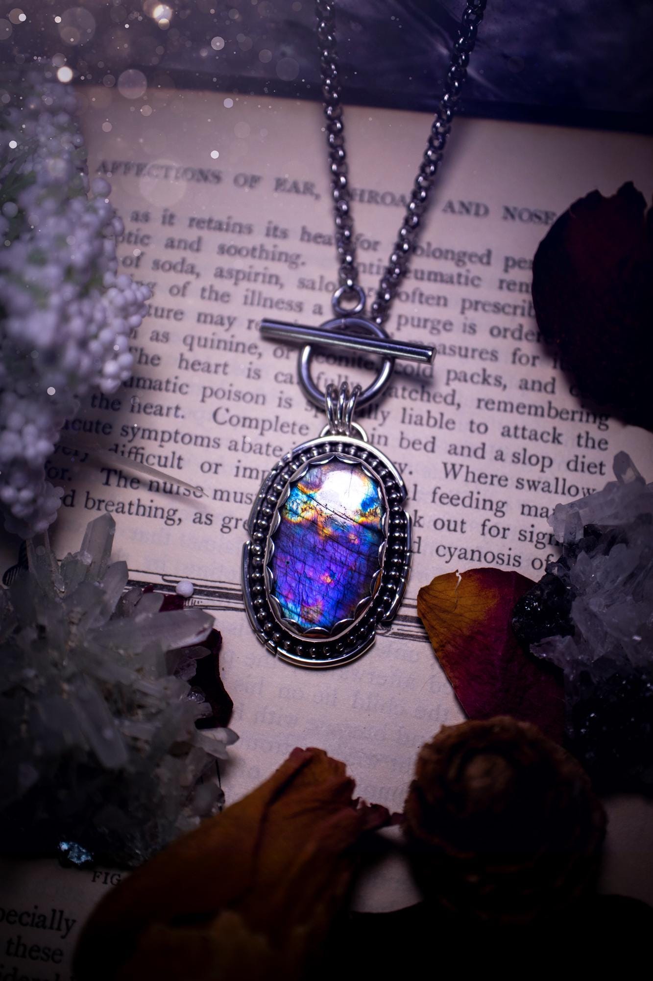 Beautifully handmade, amulet pendant necklace which features the most beautiful rainbow coloured, labradorite spectrolite crystal. This pendant has been handcrafted using a mix of fine and sterling silver. It features a scallop bezel with beaded, and hand carved smooth wire around the stone making this piece totally bespoke and one of a kind. The labradorite has an array of beautiful purples, blues and pinks. This pendant would be suitable for any crystal and jewellery lover, gothic and hippy!