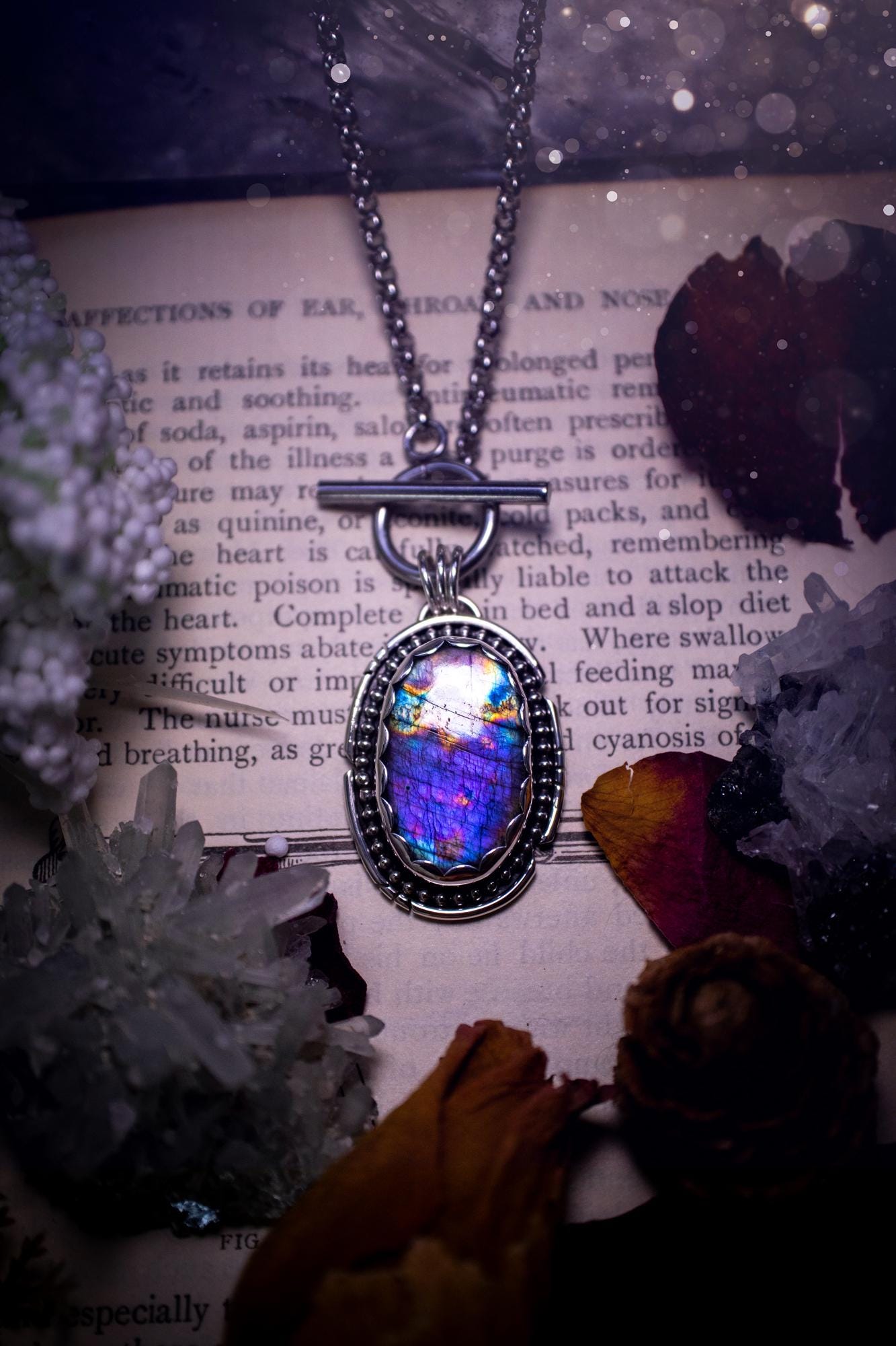 Beautifully handmade, amulet pendant necklace which features the most beautiful rainbow coloured, labradorite spectrolite crystal. This pendant has been handcrafted using a mix of fine and sterling silver. It features a scallop bezel with beaded, and hand carved smooth wire around the stone making this piece totally bespoke and one of a kind. The labradorite has an array of beautiful purples, blues and pinks. This pendant would be suitable for any crystal and jewellery lover, gothic and hippy!