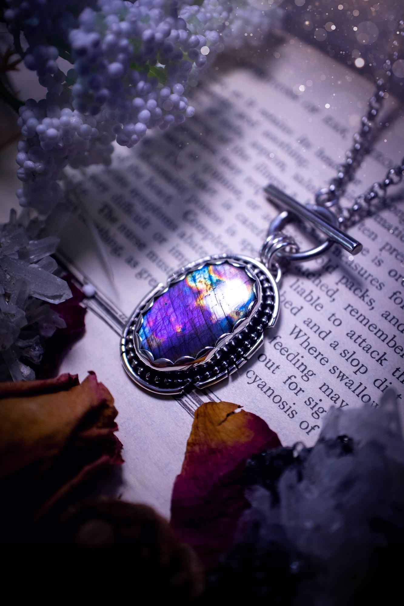 Beautifully handmade, amulet pendant necklace which features the most beautiful rainbow coloured, labradorite spectrolite crystal. This pendant has been handcrafted using a mix of fine and sterling silver. It features a scallop bezel with beaded, and hand carved smooth wire around the stone making this piece totally bespoke and one of a kind. The labradorite has an array of beautiful purples, blues and pinks. This pendant would be suitable for any crystal and jewellery lover, gothic and hippy!