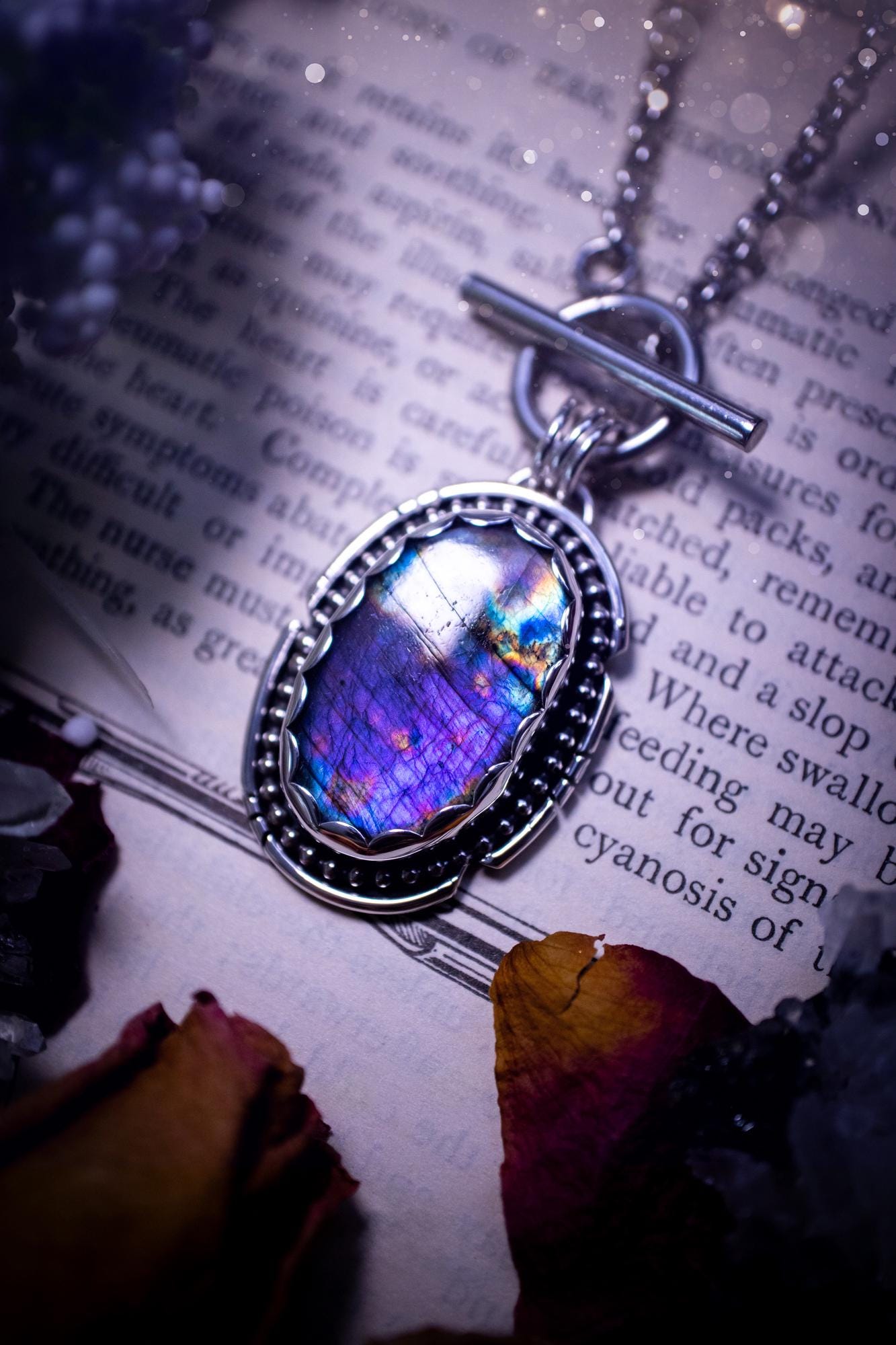 Beautifully handmade, amulet pendant necklace which features the most beautiful rainbow coloured, labradorite spectrolite crystal. This pendant has been handcrafted using a mix of fine and sterling silver. It features a scallop bezel with beaded, and hand carved smooth wire around the stone making this piece totally bespoke and one of a kind. The labradorite has an array of beautiful purples, blues and pinks. This pendant would be suitable for any crystal and jewellery lover, gothic and hippy!