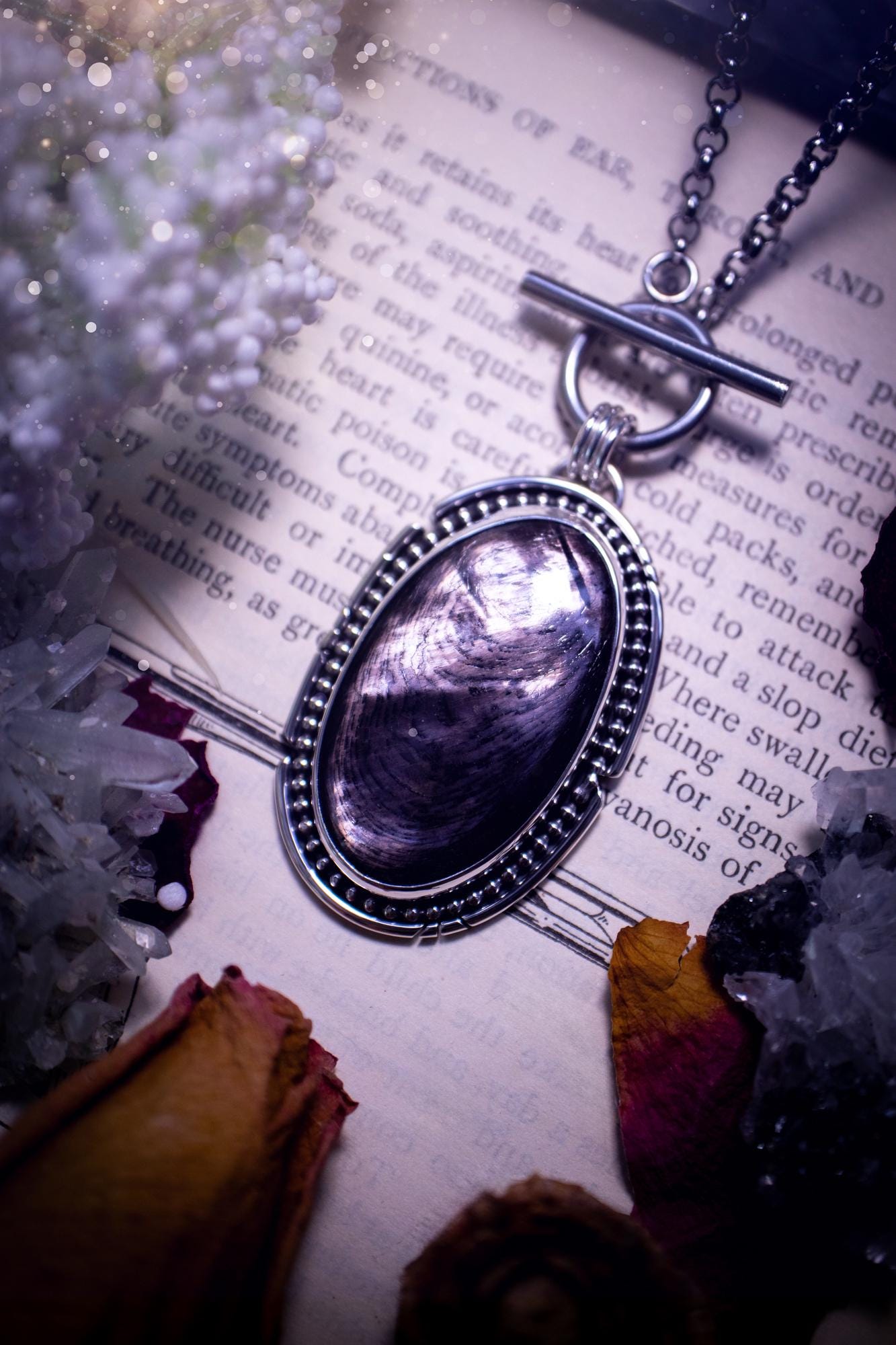 Beautifully handmade, amulet pendant necklace which features the most beautiful, flashy hypersthene crystal gemstone. This pendant has been handcrafted using a mix of fine and sterling silver. It features a smooth bezel with beaded, and hand carved smooth wire around the stone making this piece totally bespoke and one of a kind. The hypersthene has an array of beautiful greys and blacks. This pendant would be suitable for any crystal and jewellery lover, full of gothic and witchy vibes.