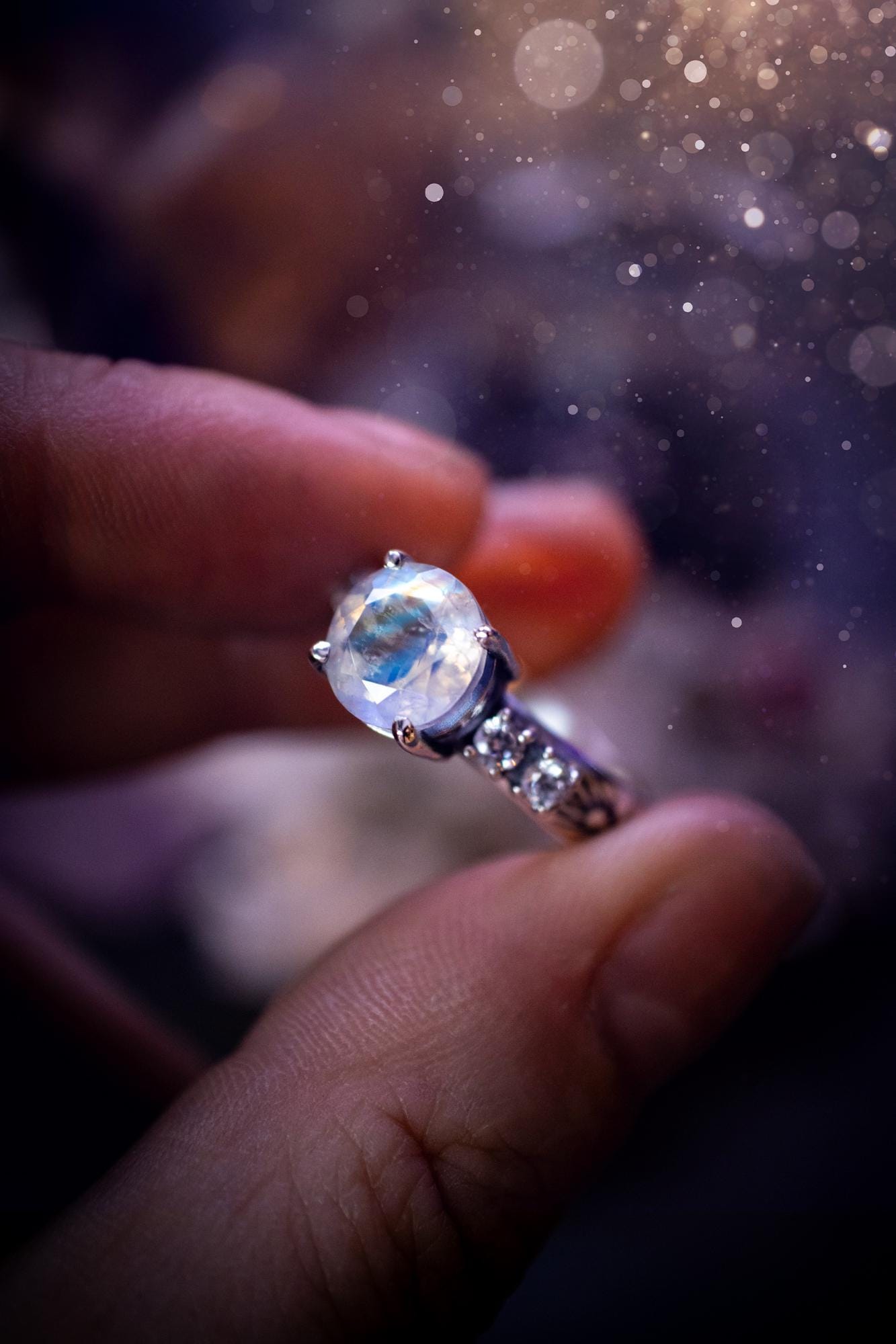 Beautifully handmade, and bespoke, natural rainbow moonstone statement ring. This one of a kind ring has been handmade using a mix of fine and sterling silver. Featuring a beautiful, flashy round, natural rainbow moonstone crystal that has stunning hues of blue, along with cubic zirconia to the sides of the crystal. The ring band is stamped with unique detailing. The ideal treat and gift for anyone who is a lover of crystals and jewellery. This ring is full of gothic and witchy vibes!