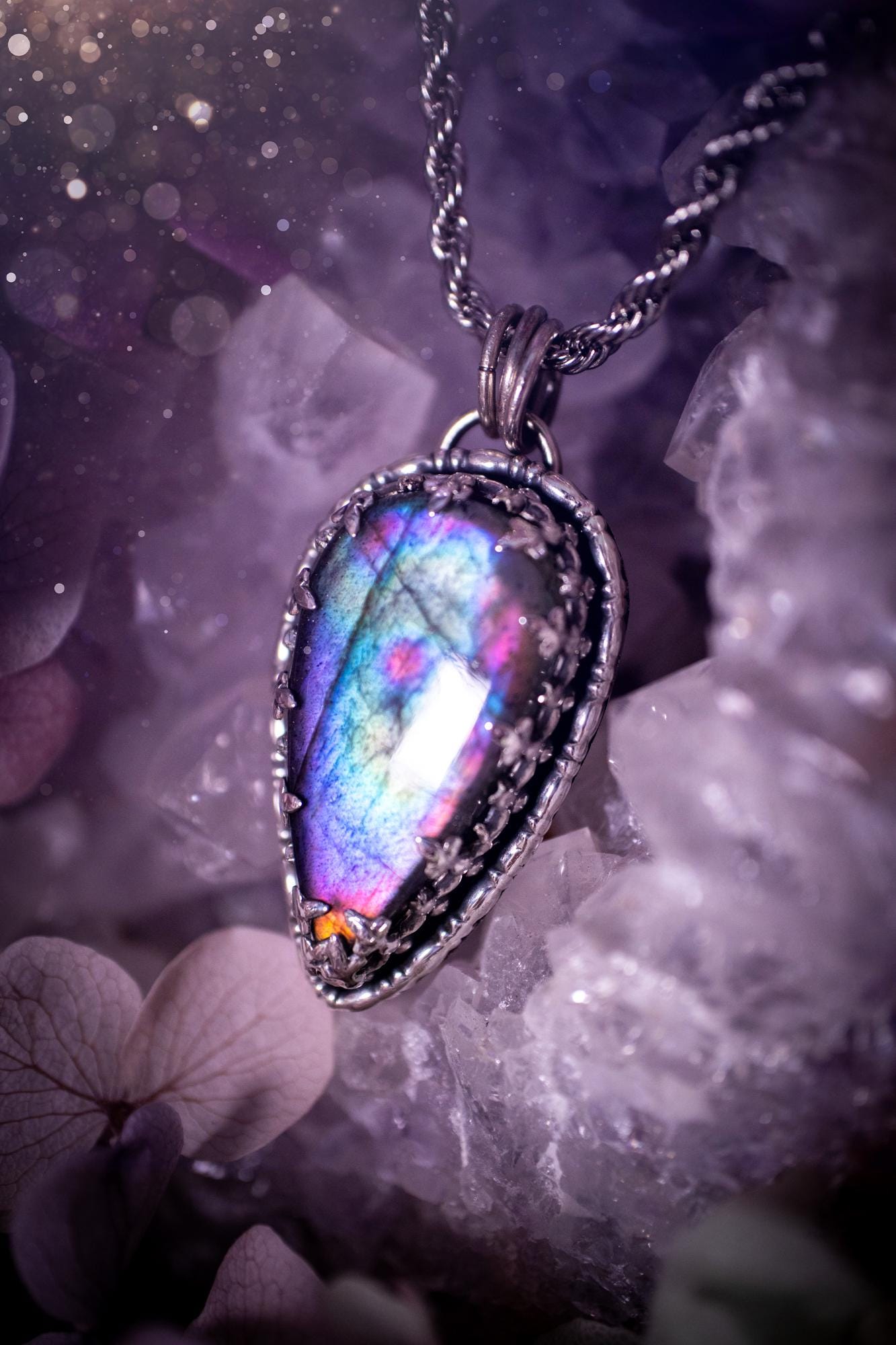 Beautifully handcrafted, rainbow labradorite crystal pendant necklace. This beautiful pendant has been crafted out of sterling and fine silver and features a gothic bezel around the labradorite crystal. The labradorite in this piece is full of beautiful colours, purple, greens, blues with a bit of orange! A really stunning crystal. This jewellery piece would be ideal for anyone who is a fan of jewellery and crystals, and would make the ideal gift. Full of witchy and gothic vibes!