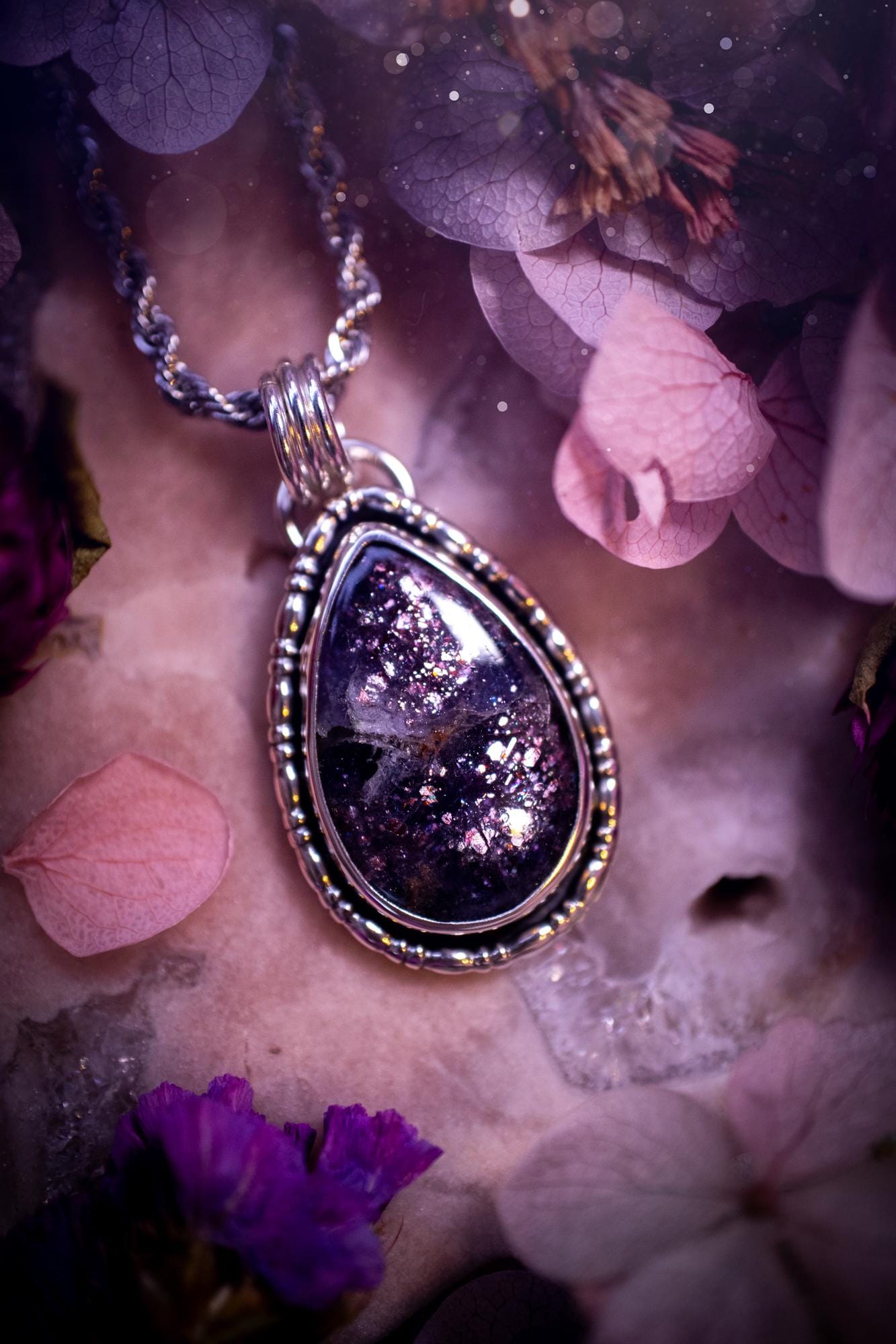 Stunning and handcrafted, natural Iolite sunstone, crystal pendant necklace. This beautiful pendant features a very sparkly iolite sunstone crystal that looks just like the galaxy, full of sparkle and pink shimmer. Made from a mix of sterling and fine silver, this piece is full of gothic vibes and has a gothic gallery wire around the crystal. Small and dainty. This piece would be suitable for gifting to jewellery and crystal lovers. Very witchy, gothic and hippy!