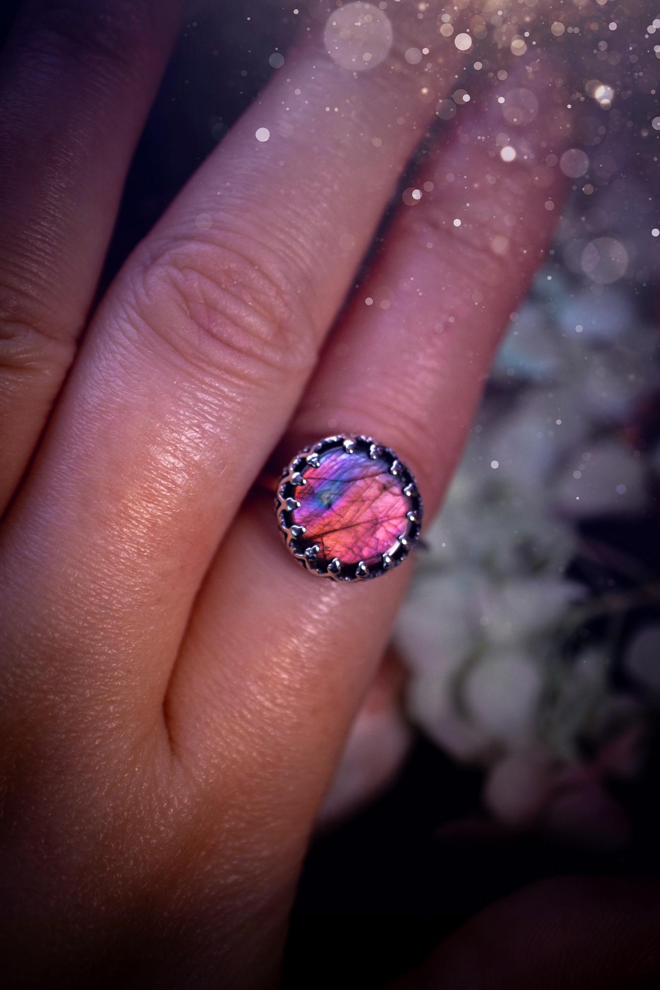 Handmade and very gothic, natural purple labradorite, sterling silver ring. This minimalist ring features a very pretty and flashy labradorite crystal that has a rich and vibrant purple colour. Around the crystal is a beautifully detail, gothic bezel that has been polished to a high lustre. The crystal is mounted on a 1.50mm ring shank. This ring would be ideal for anyone who loves jewellery and crystals, or who has a gothic and witchy style. A beautiful piece of jewellery to add to a collection