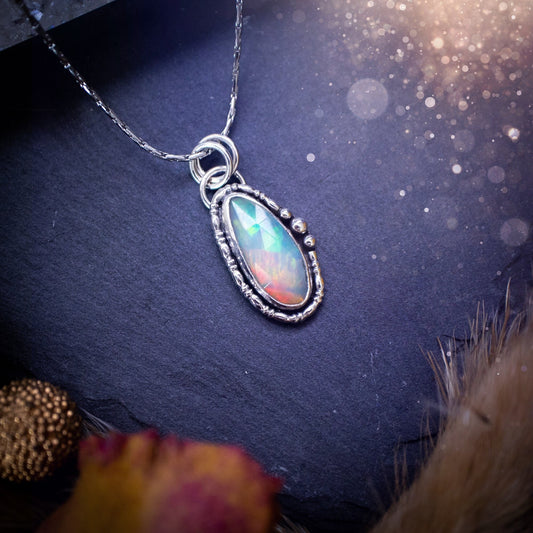 Flashy, natural, rose cut Ethiopian Welo Opal pendant necklace. This beautiful piece of jewellery is hand made, and has been created out of sterling silver. Accompanying this crystal is silver ball and wire components, making an ideal gift for hippys