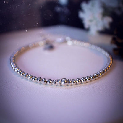 Beautiful and handmade, 3mm beaded, sterling silver stacking bracelet. This bracelet has been made using high quality sterling silver beads which have bee strung on strong 49 strand beading wire. This wire is very strong, but also gives a beautiful drape across the wrist. Featuring one larger silver spacer bead in the middle with rondelle beads either side to give some uniqueness. This bracelet is ideal for stacking with others, and makes a lovely gift for jewellery lovers.