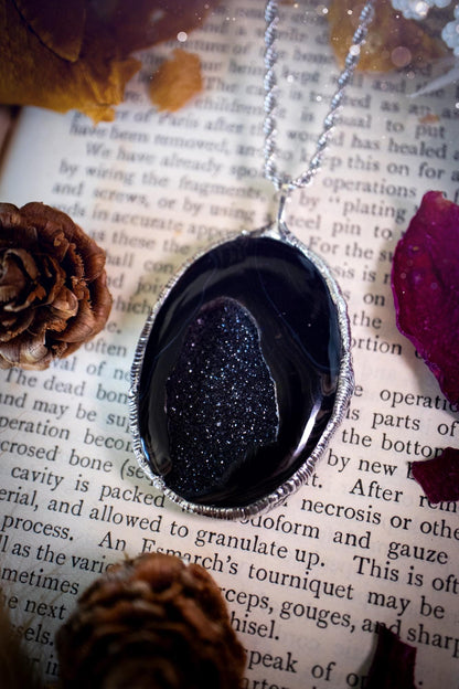 Beautiful and handcrafted, black druzy agate, crystal pendant necklace. This one of a kind piece of jewellery has been hand made using the tiffany technique, also known as soft soldering. The bezel is made with a solder that is lead free and contains elements of silver so when polished a high lustre is achieved. Featuring a large druzy agate with beautiful sparkle and banding. This is the ideal gift for any crystal or jewellery lover that likes a gothic and witchy vibe and aesthetic.